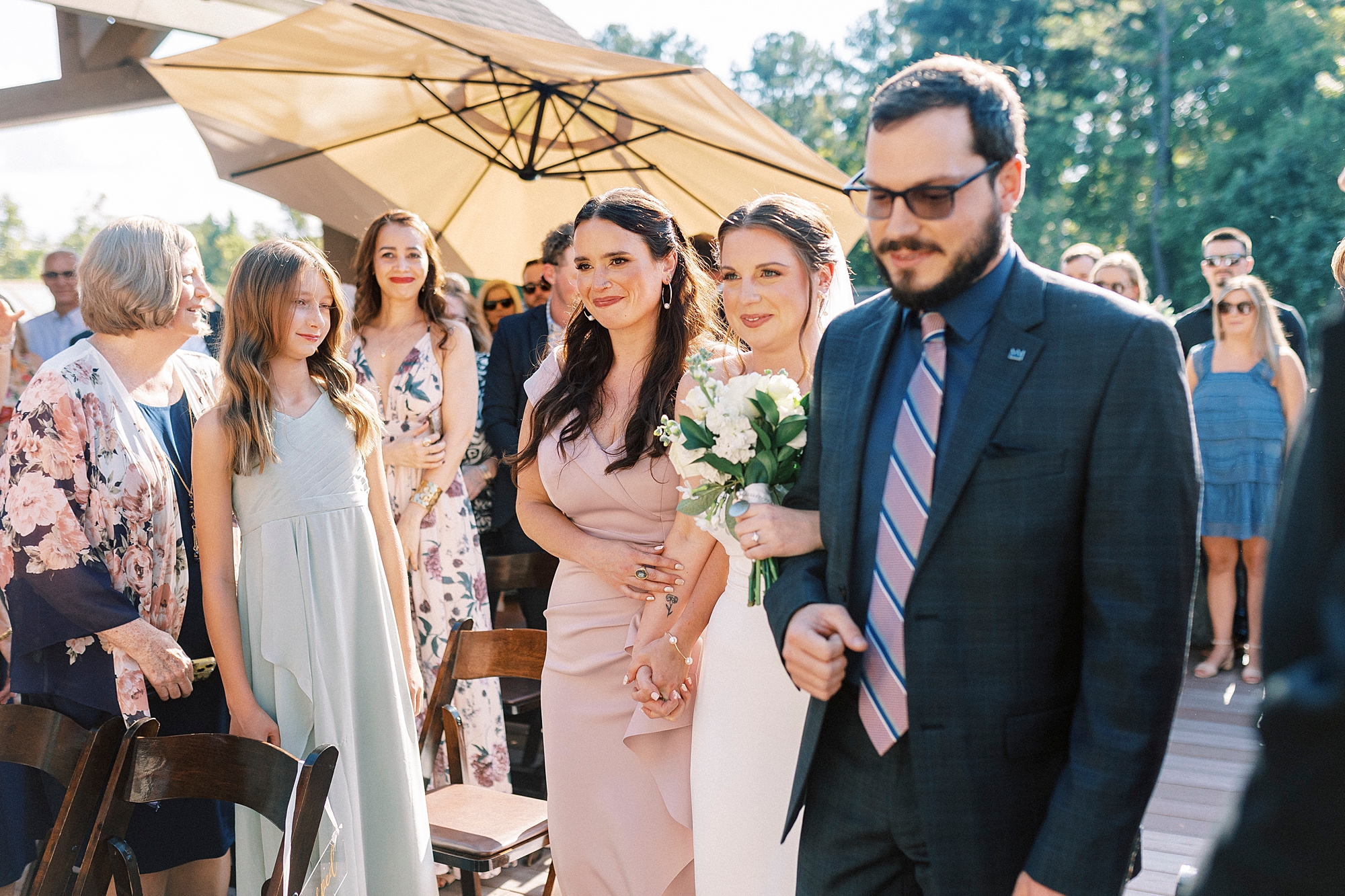 siblings walk bride down the aisle outside Palisades Country Club