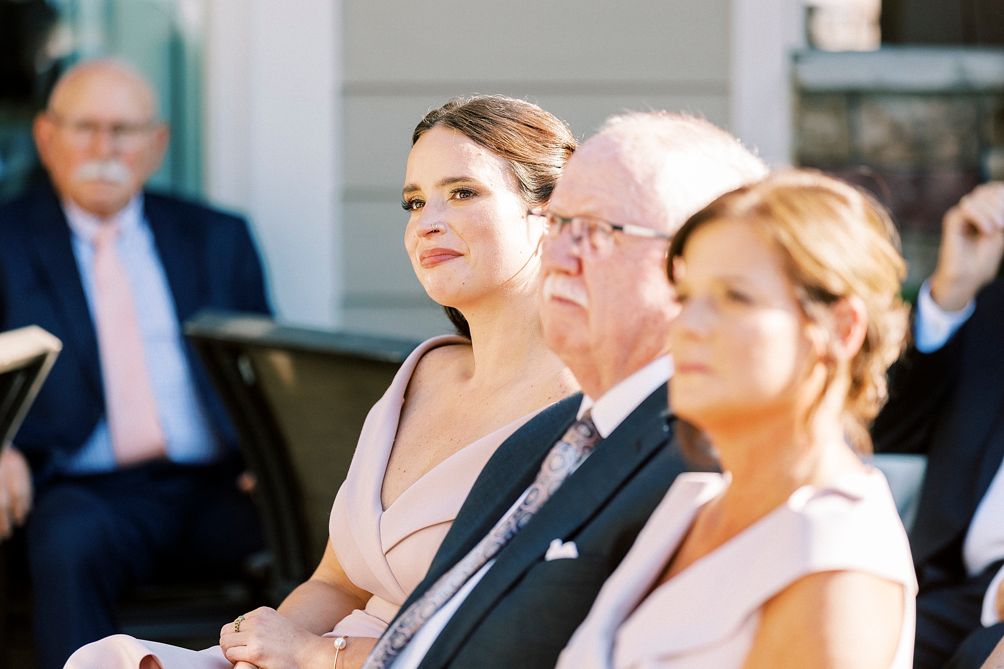 family smiles listening to wedding ceremony 