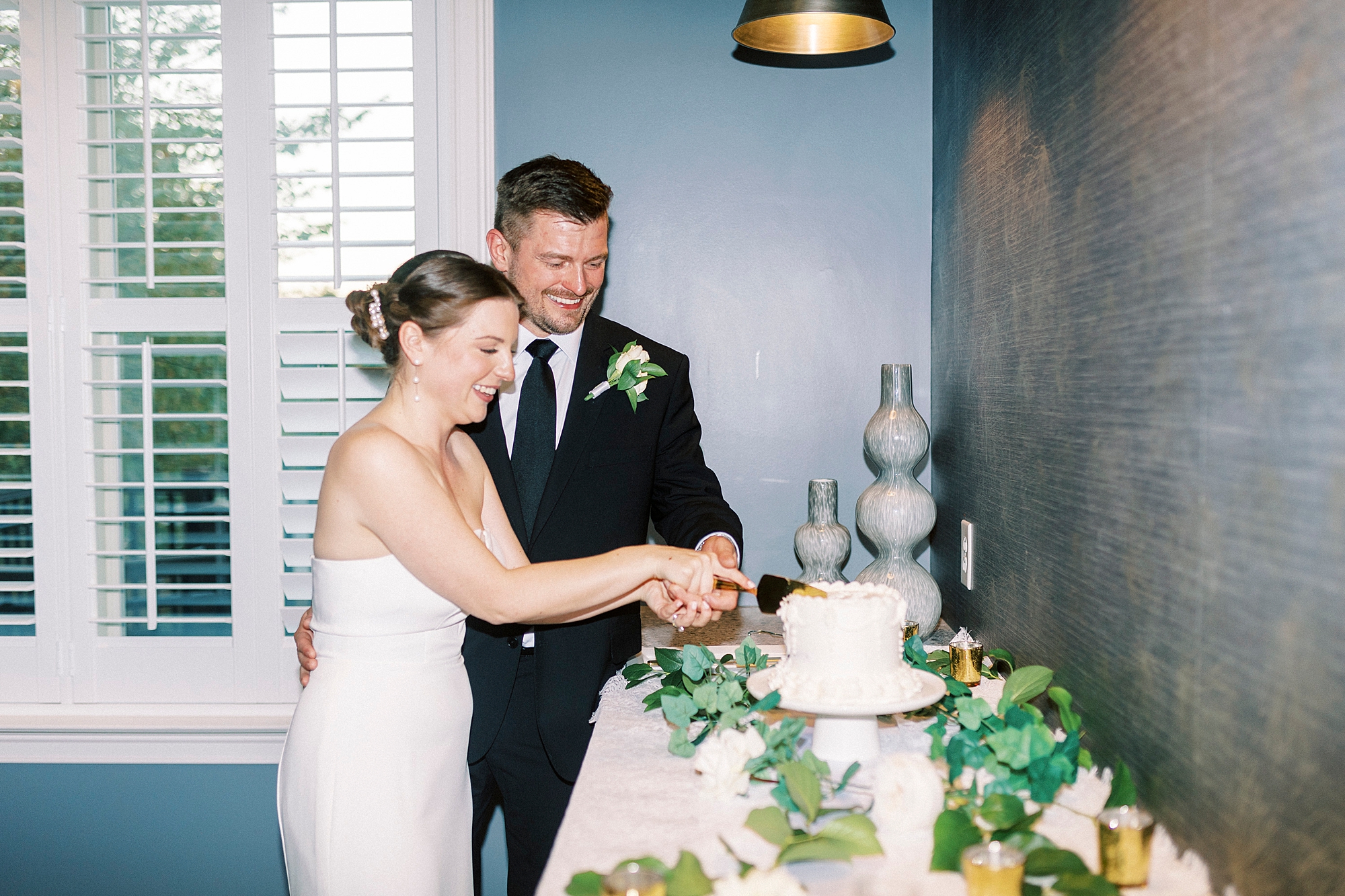 newlyweds cut wedding cake during wedding reception at Palisades Country Club