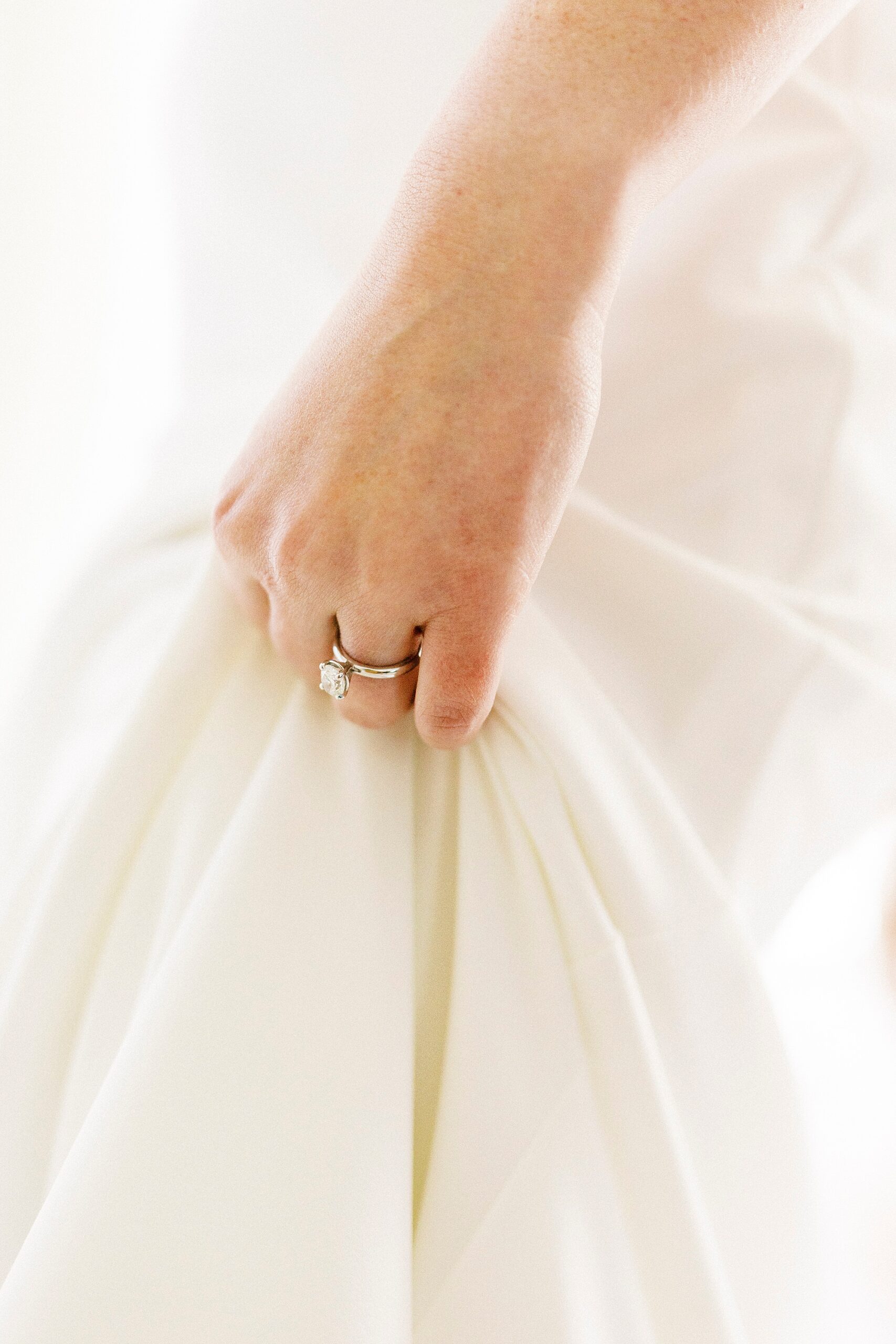 bride holds skirt of wedding gown showing off engagement ring