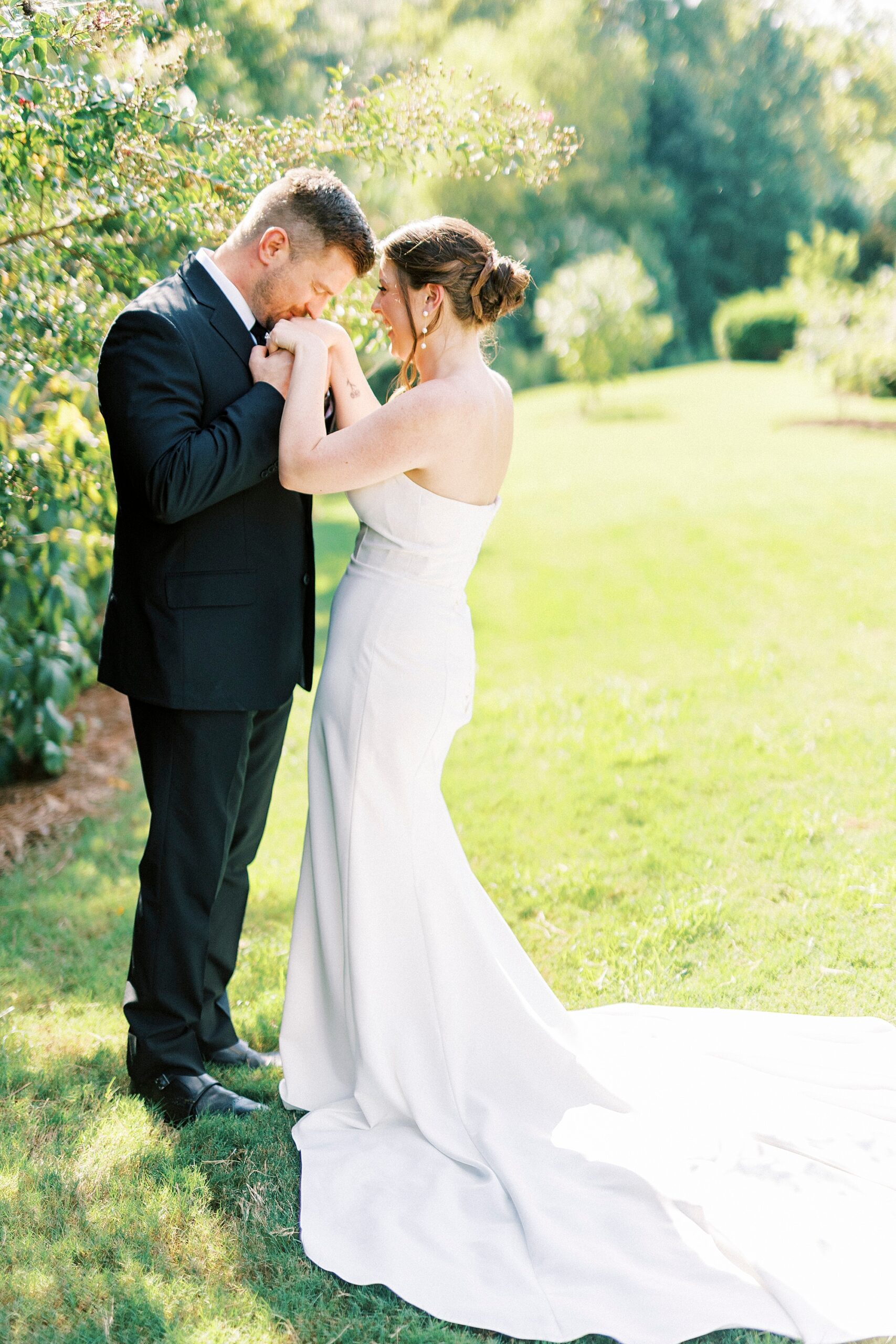 groom holds bride's hands kissing her knuckles