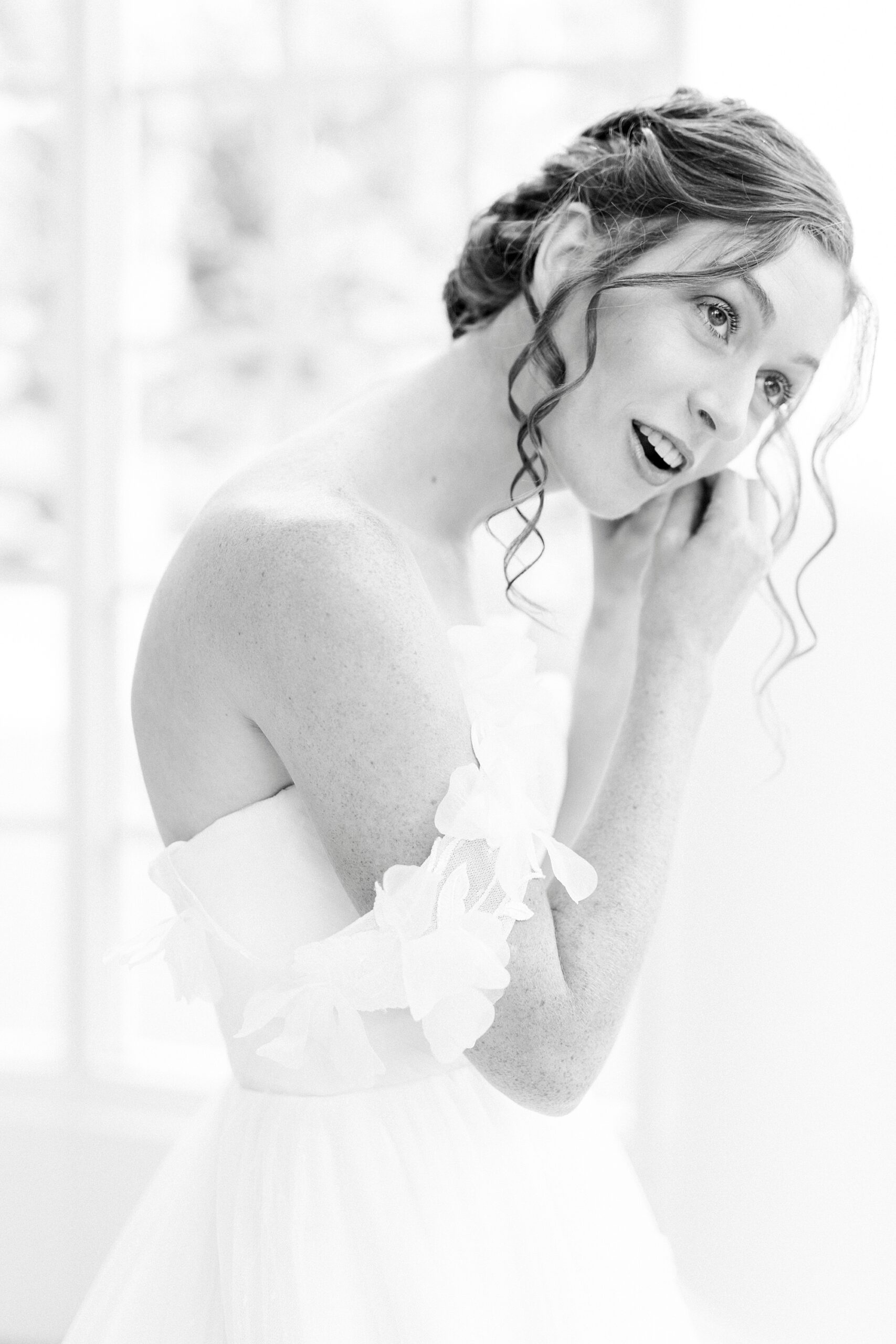 bride leans forward and adjust earrings in atrium of the Belk Chapel