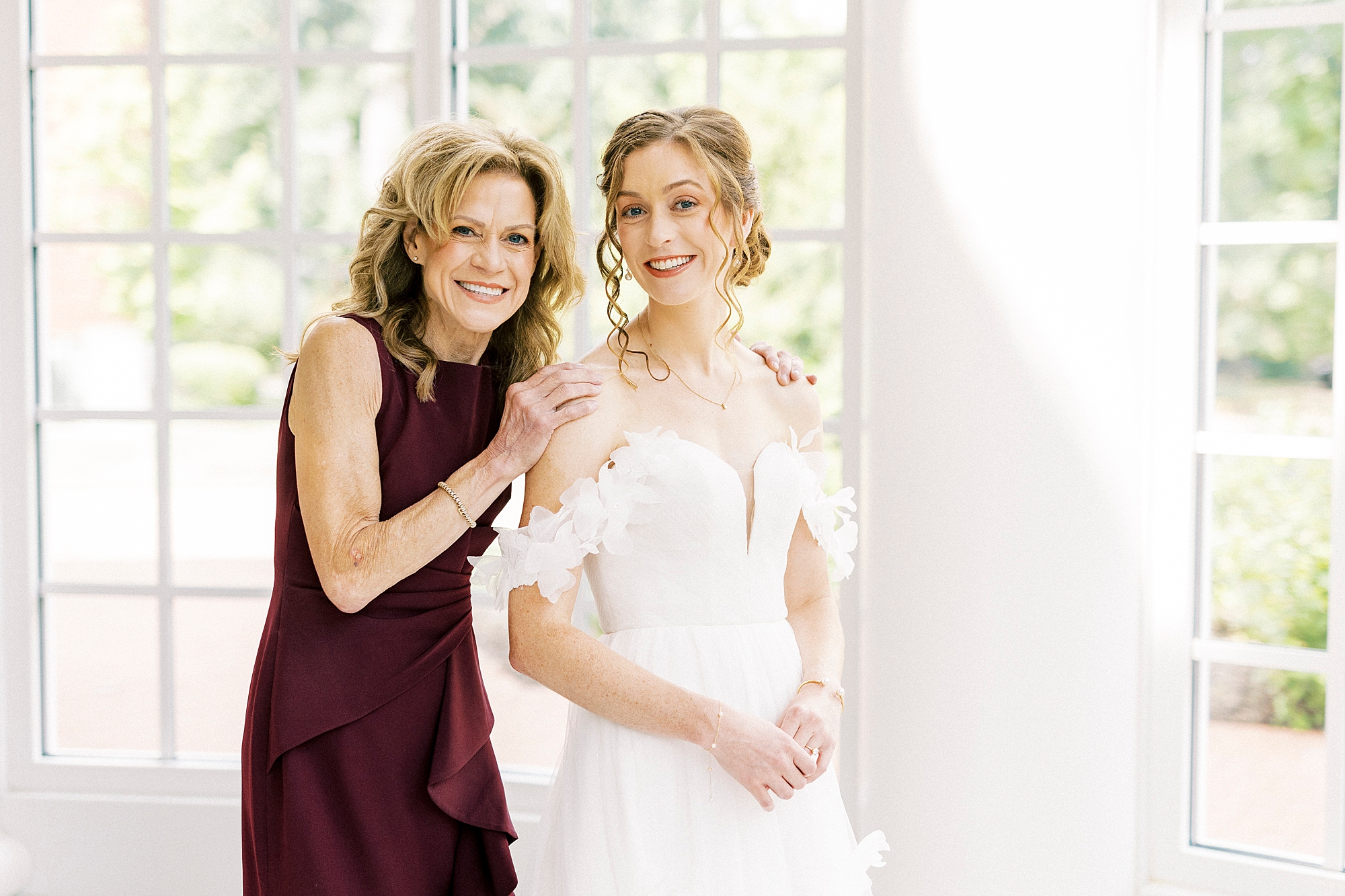bride and mom pose together inside the atrium of the Belk Chapel