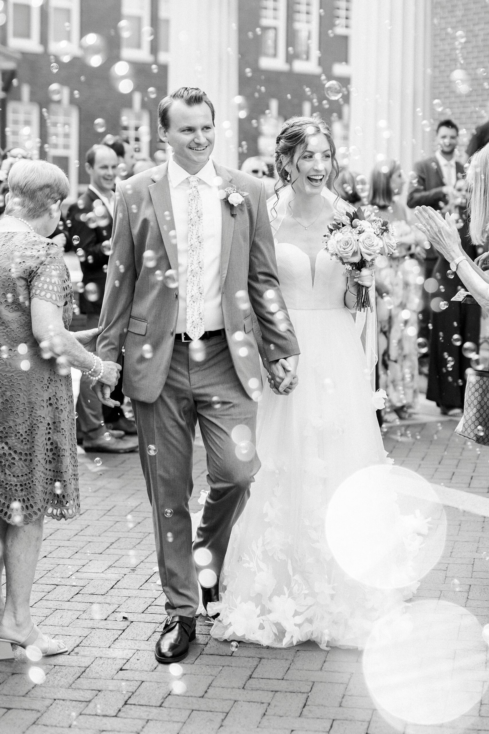 newlyweds walk through guests and bubble exit outside Belk Chapel