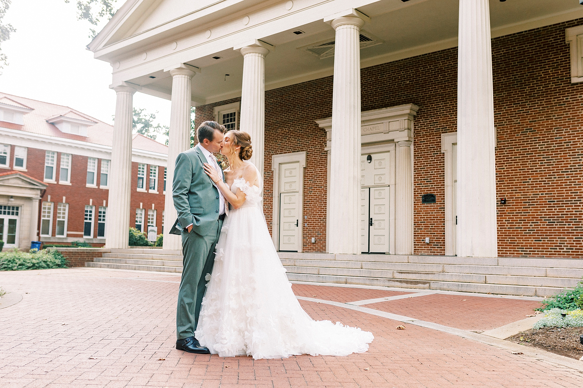 newlyweds kiss on brick patio outside Belk Chapel
