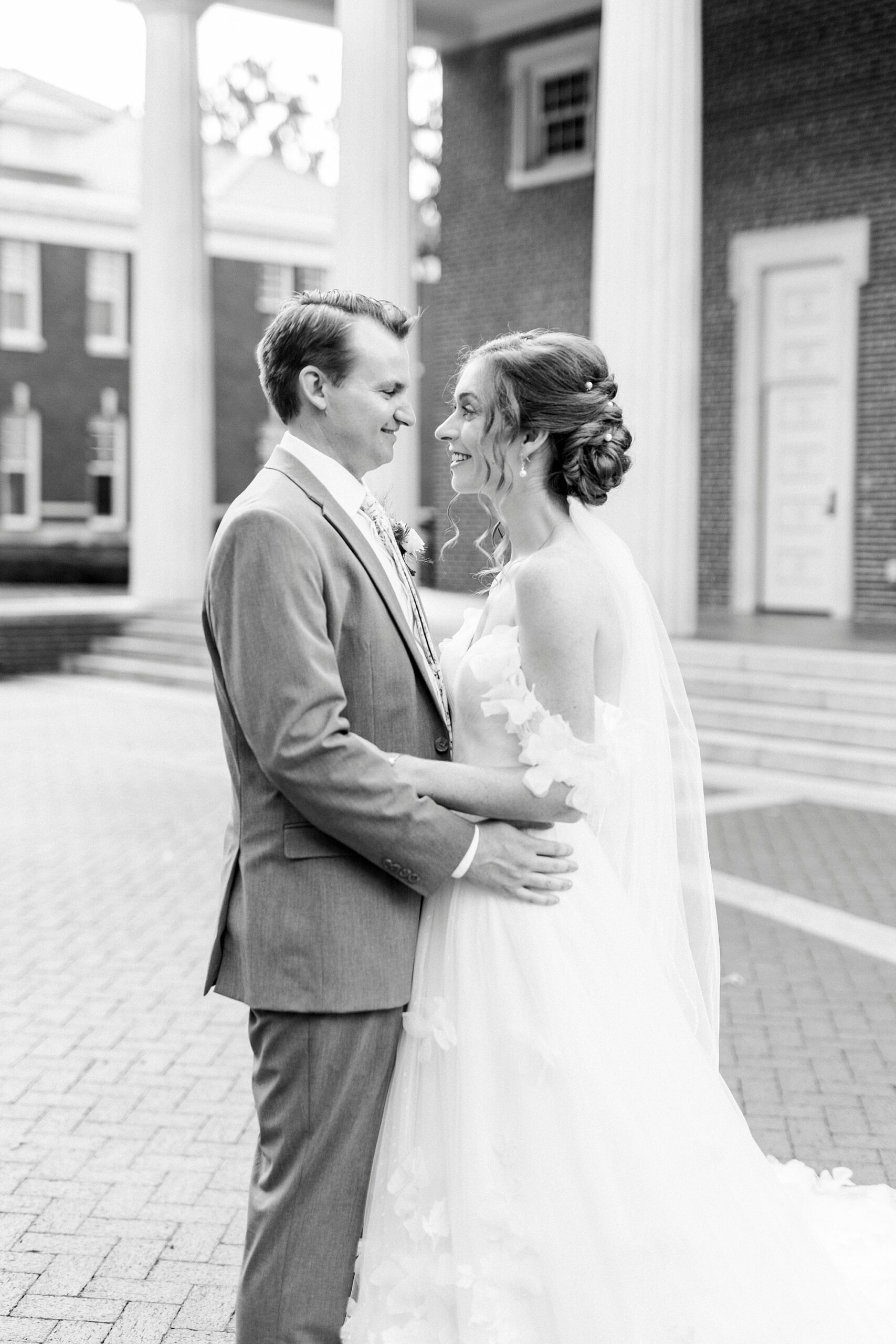 bride and groom smile at each other hugging outside Belk Chapel in Charlotte NC