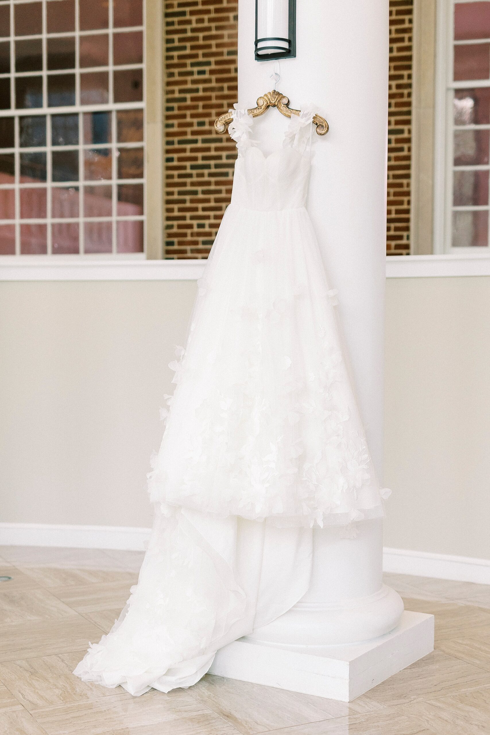 wedding dress hangs on the pillar in atrium at Belk Chapel