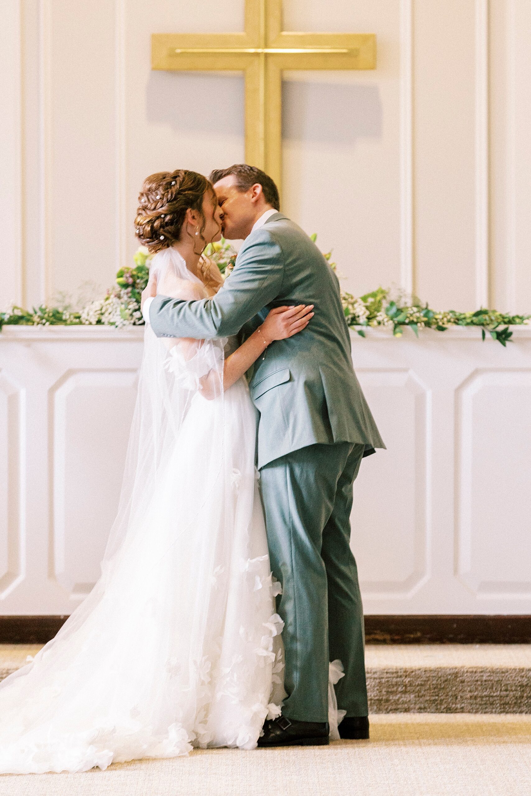 bride and groom kiss at altar during wedding ceremony at Belk Chapel