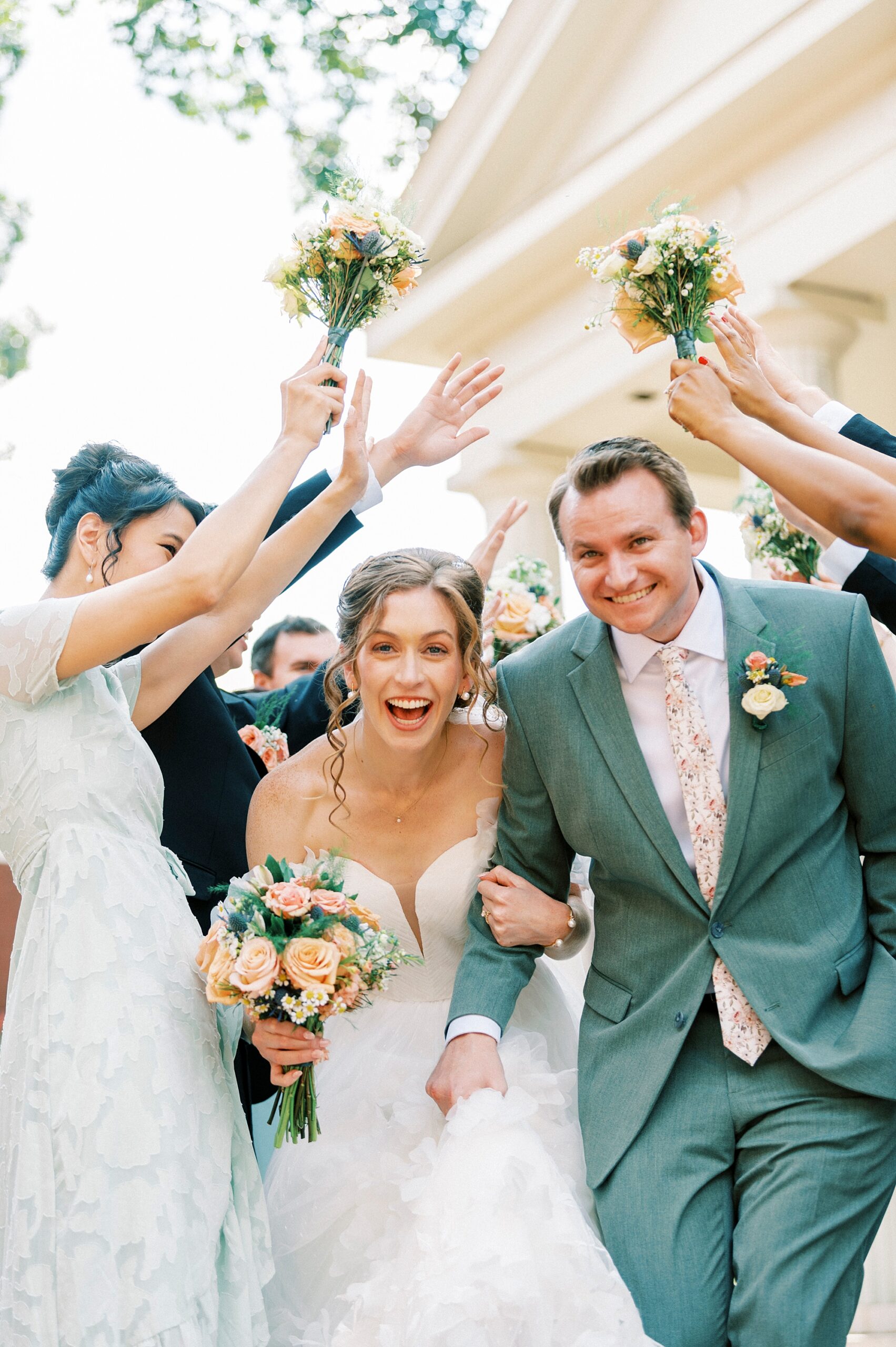 newlyweds cheer laughing walking through tunnel created by bridal party