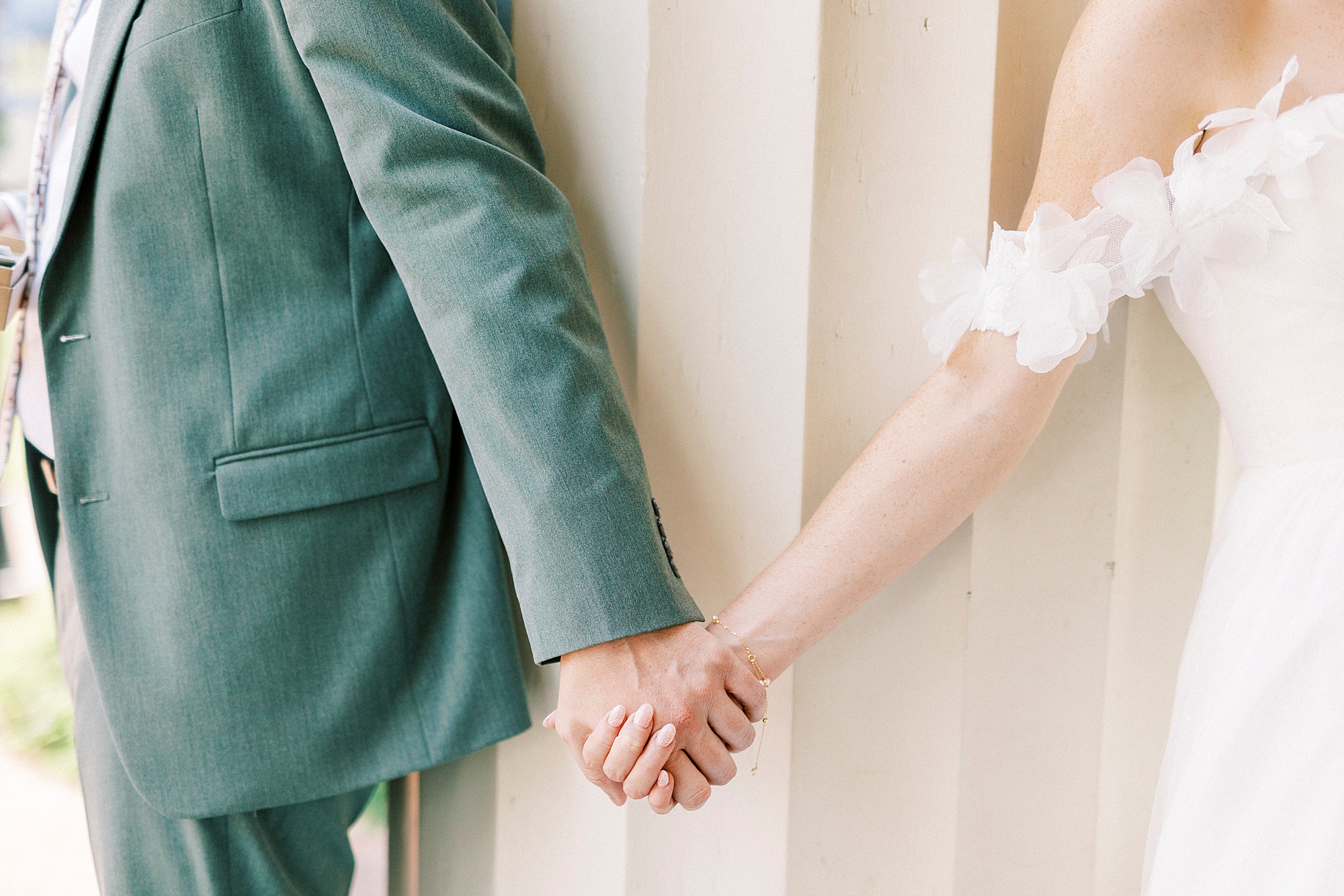couple holds hands around pillar during first look at Belk Chapel at Queens University