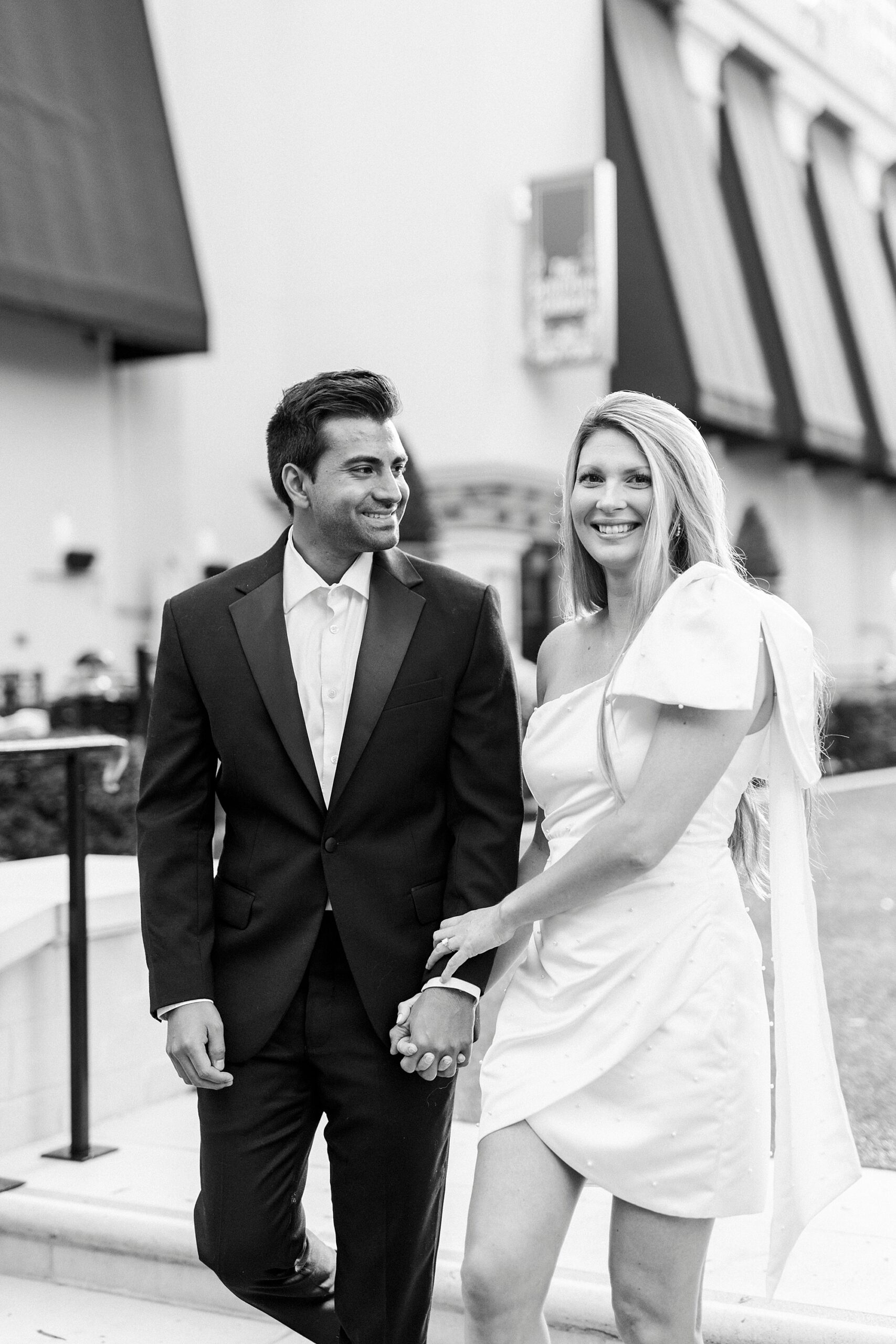 man smiles at woman in white dress walking outside the Grand Bohemian Hotel in Charlotte NC