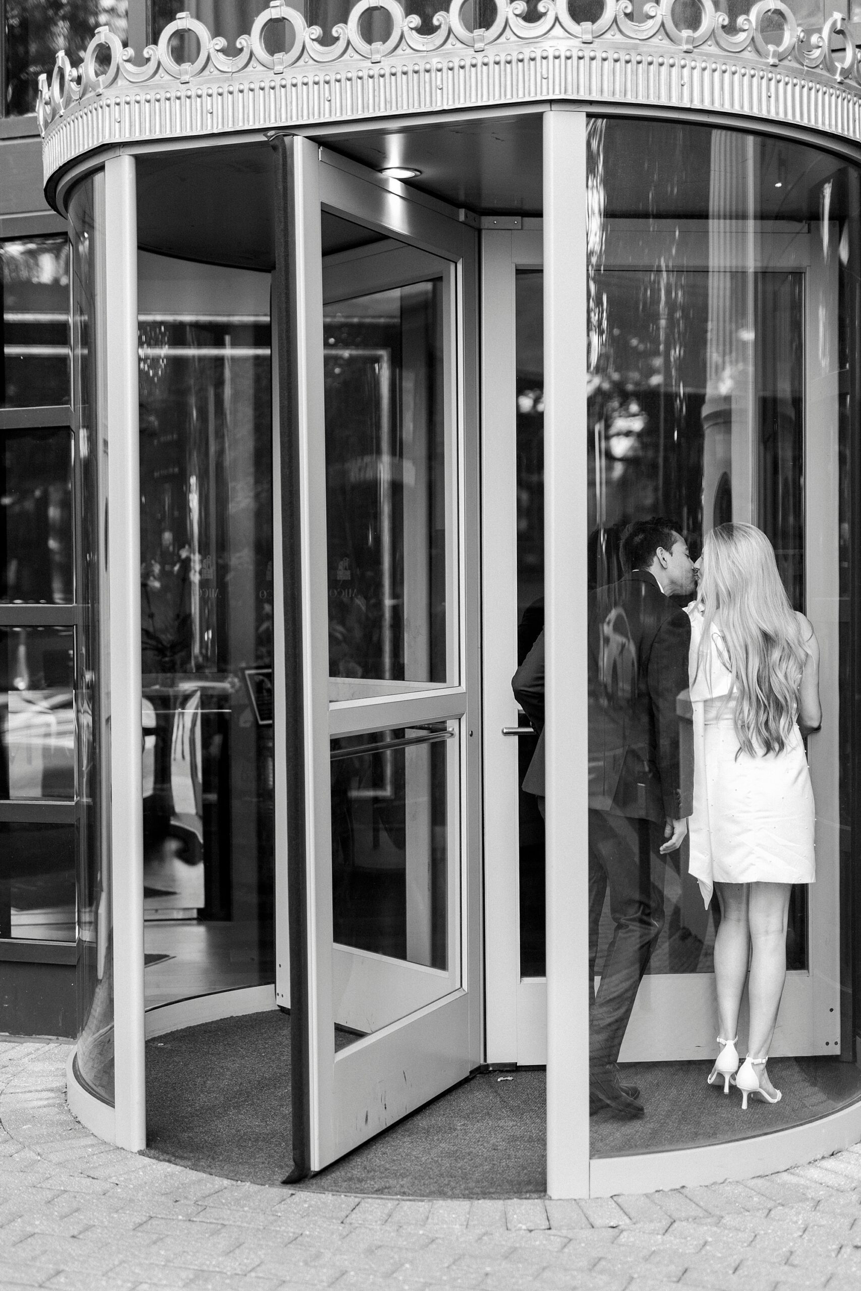 engaged couple kiss in revolving door outside the Grand Bohemian Hotel in Charlotte NC