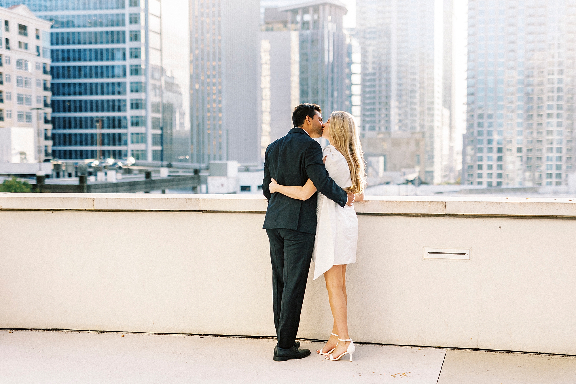 man and woman kiss overlooking the Charlotte NC skyline from the rooftop of the Grand Bohemian Hotel
