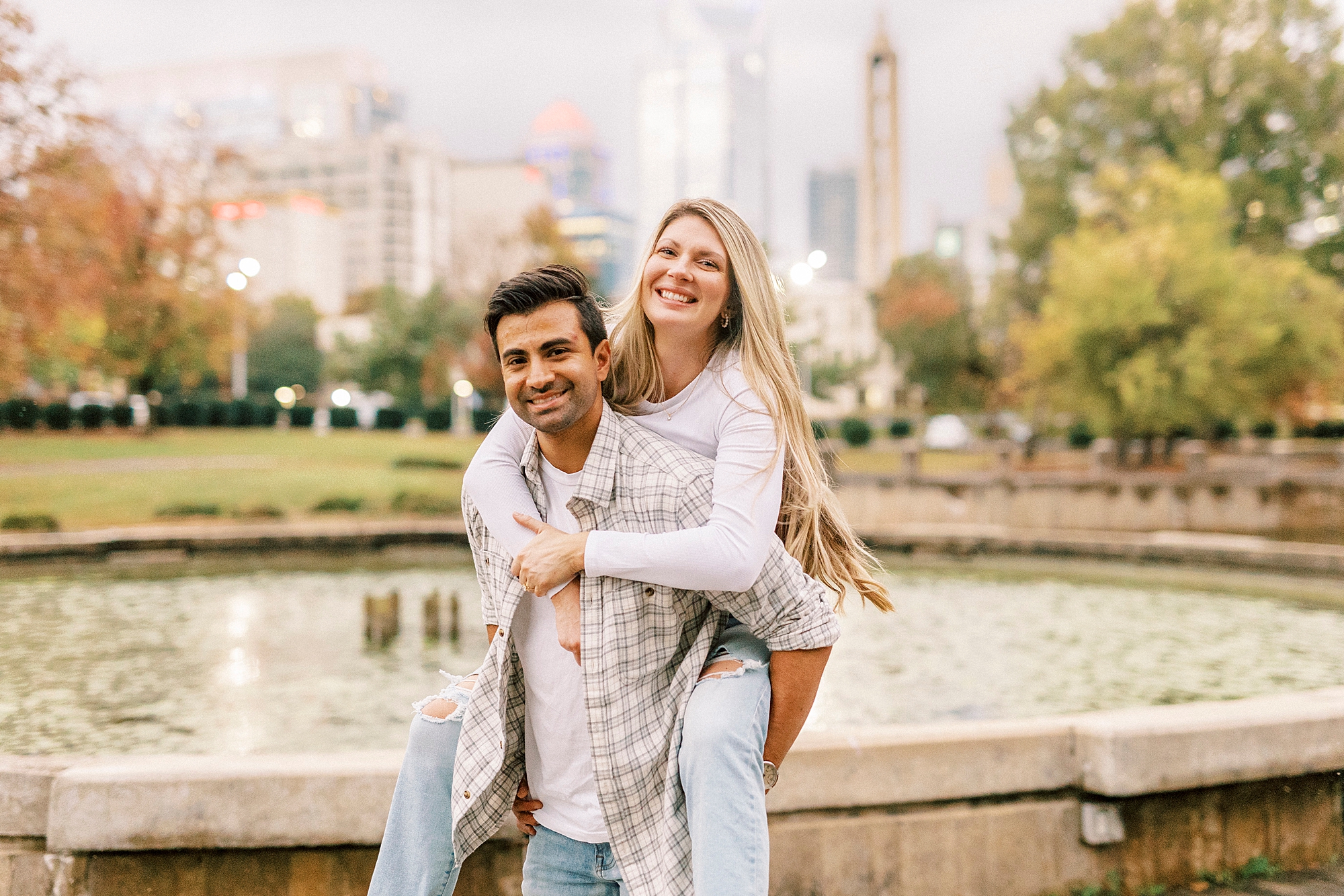 man gives woman a piggy back ride during engagement photos in Marshall Park