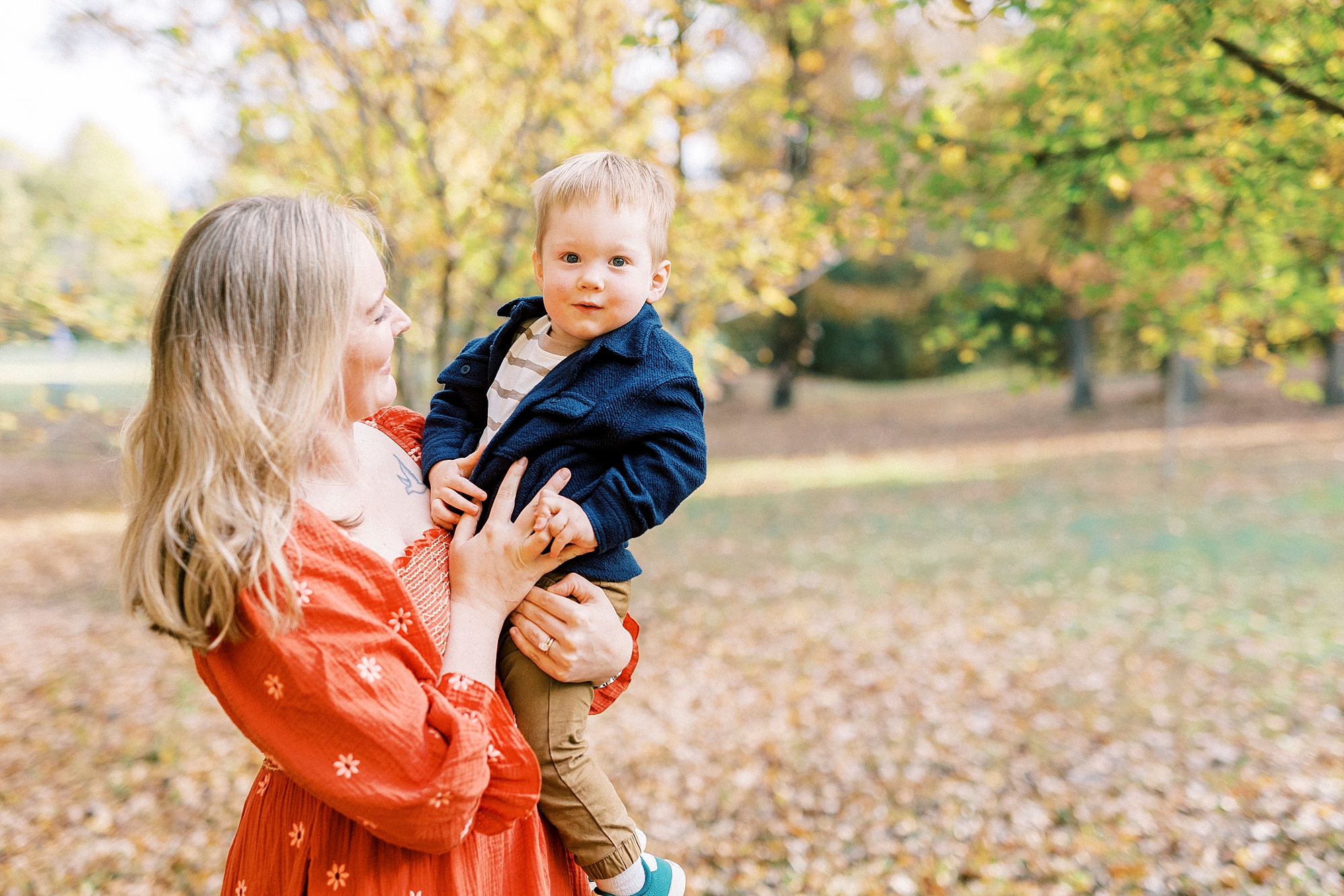 woman in burnt orange dress smiles at son during fall mini session in Charlotte NC