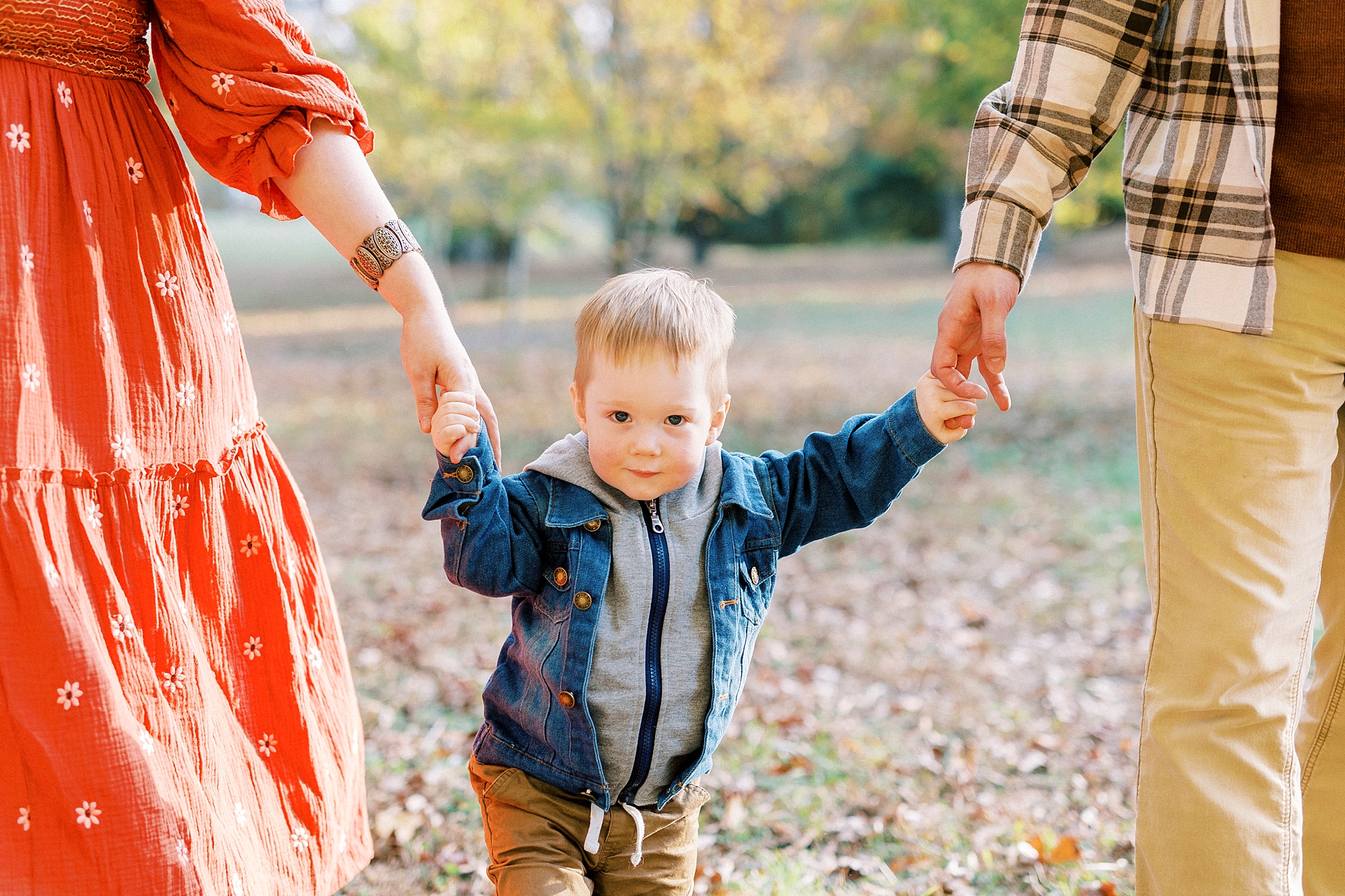 couple holds young son's hands during fall mini session in Charlotte NC