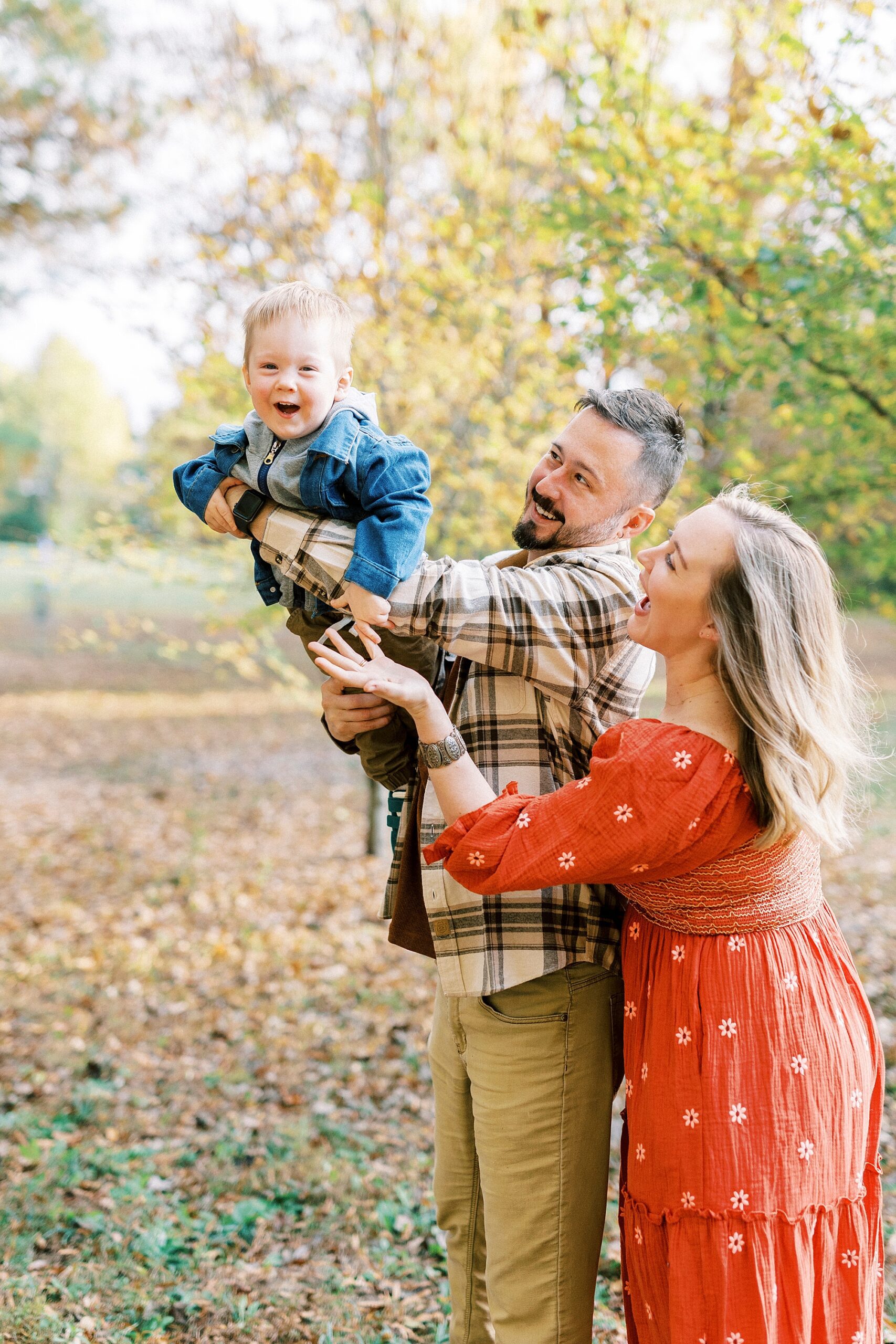 parents play with son during family photos at Rob Wallace Park for fall mini sessions in Charlotte NC