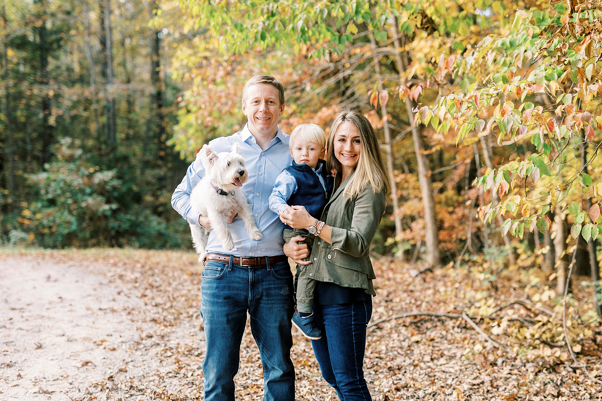 parents pose with son and white dog during fall mini session at Rob Wallace Park