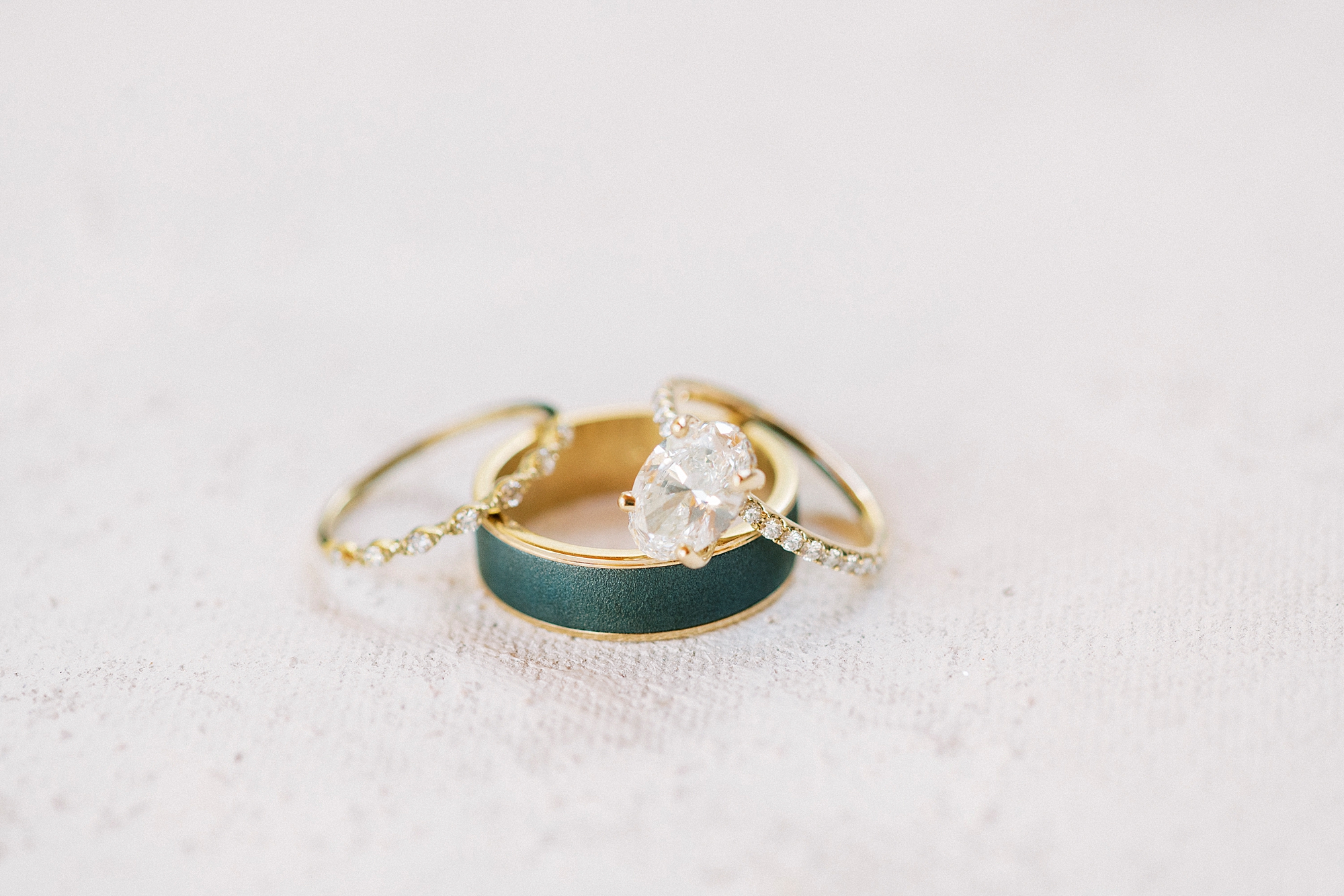 bride's gold wedding bands rest on groom's black and gold band