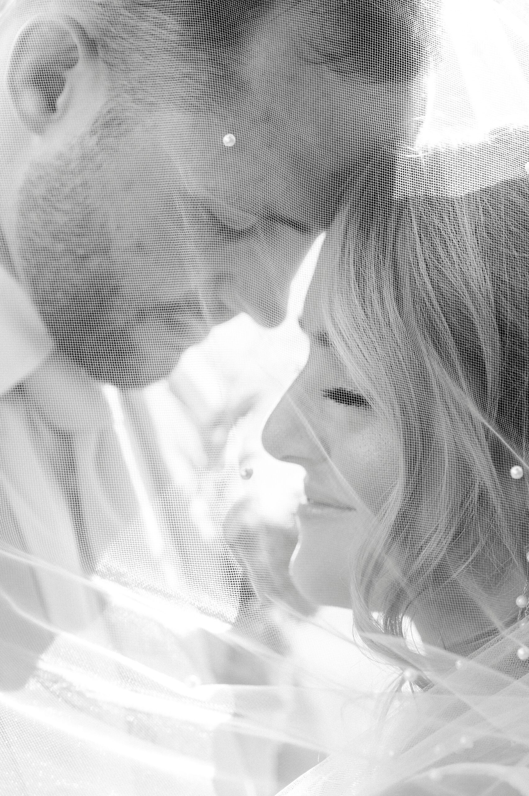 bride and groom hug under bride's veil leaning heads together 