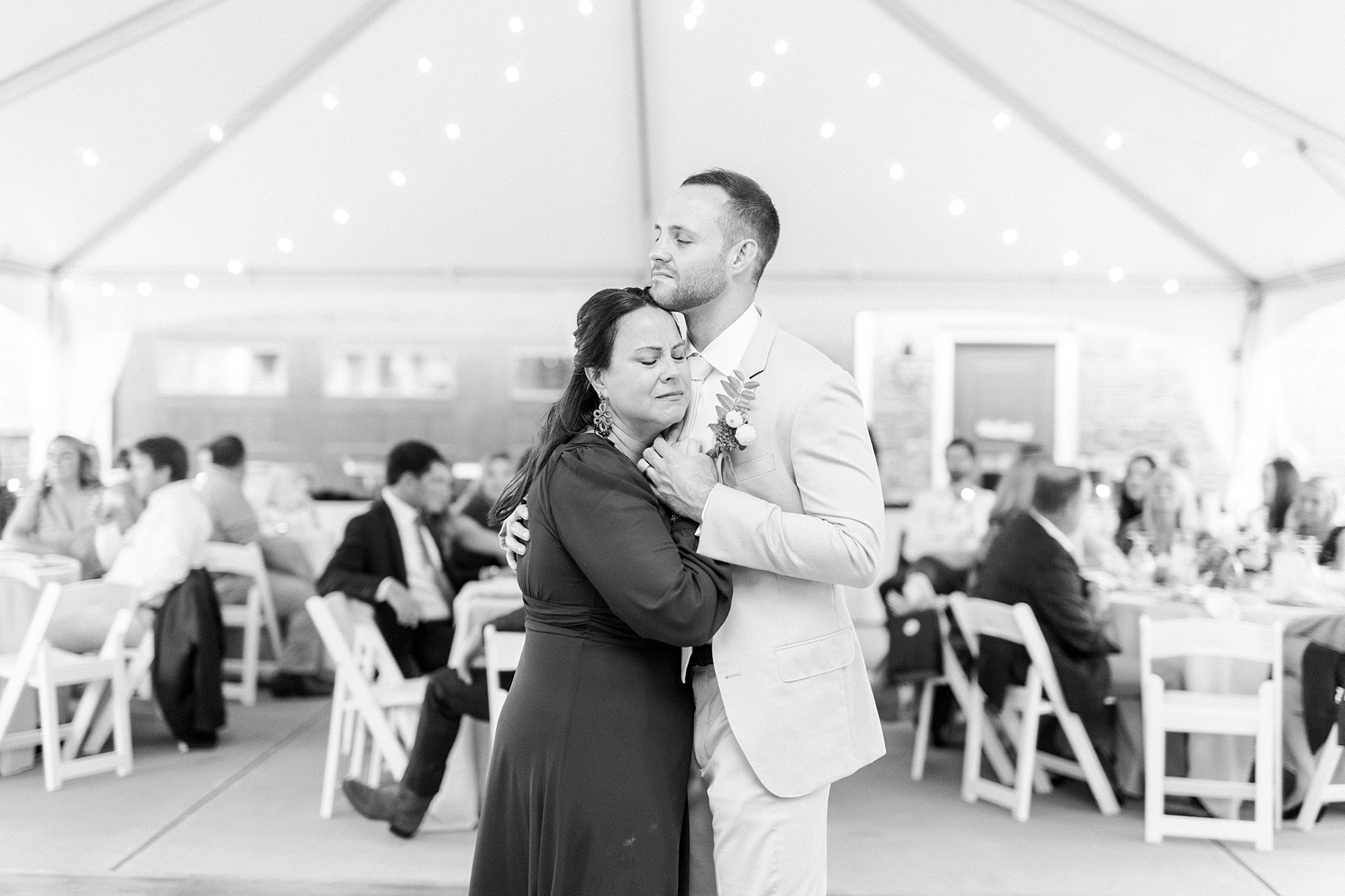 groom dances with mother under tent in backyard 