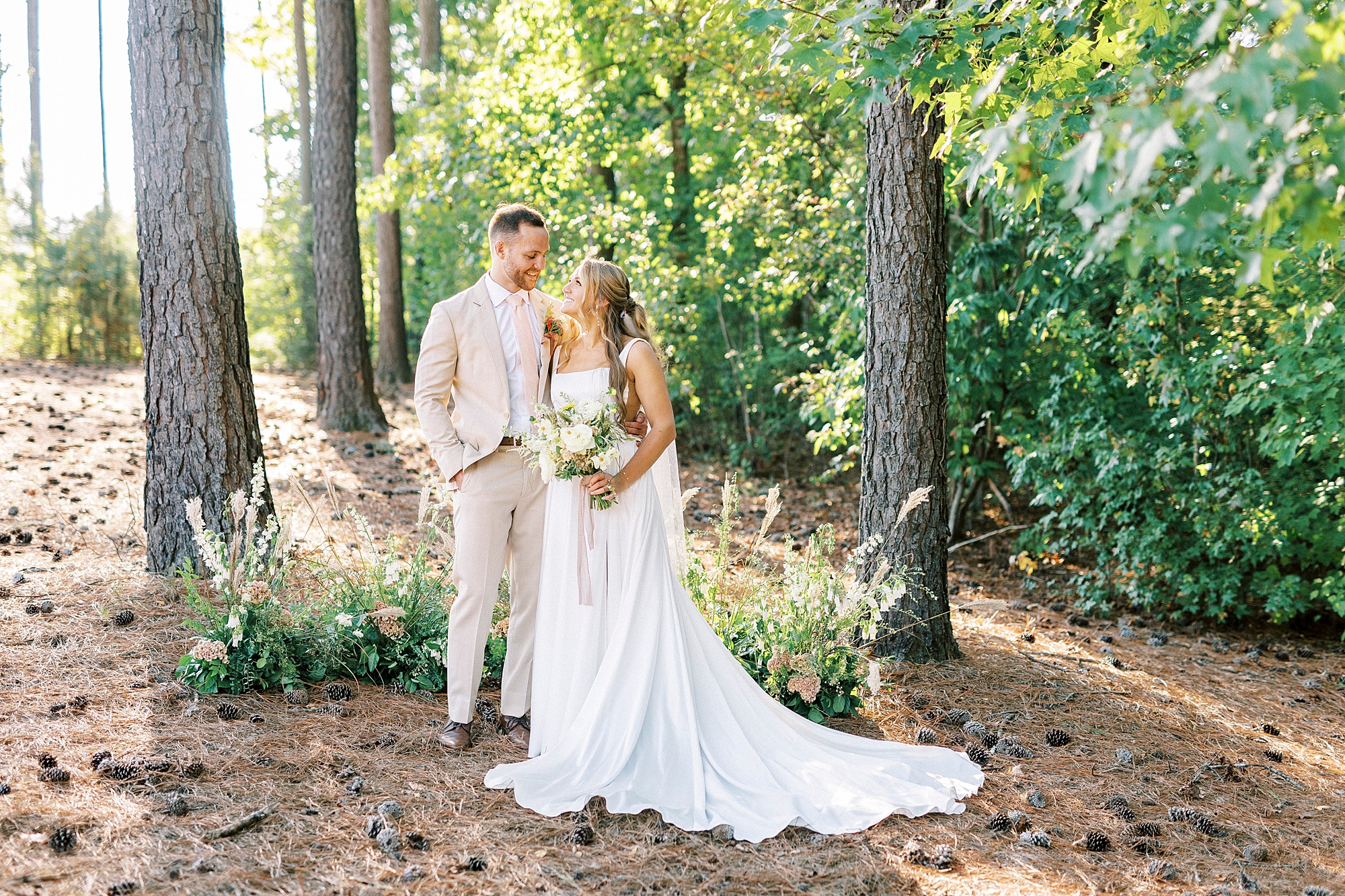 newlyweds hug between trees in backyard of home 