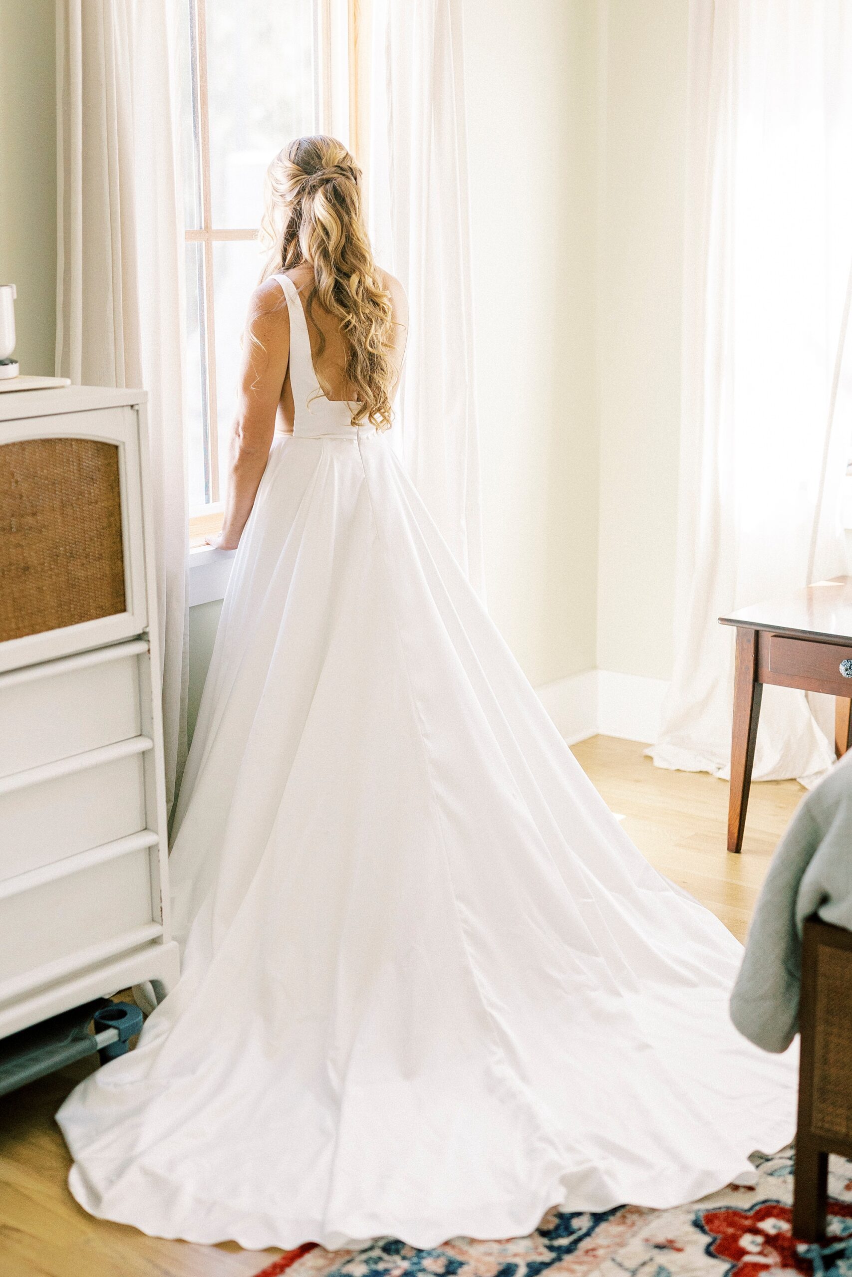 bride leans against dresser in home 