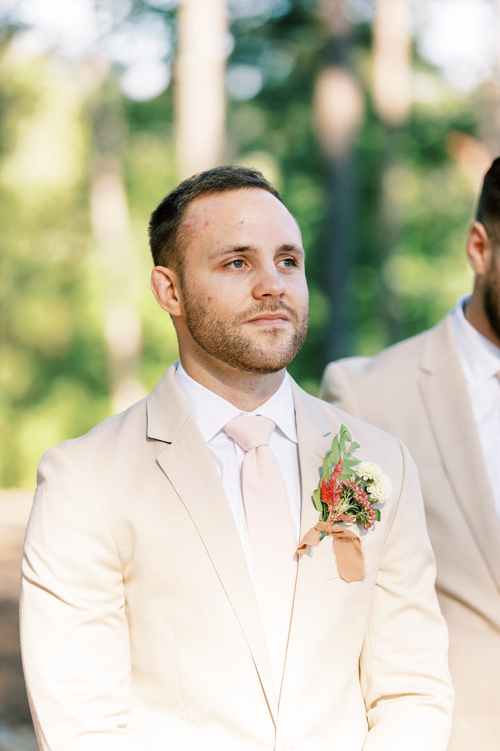 groom stands in tan suit watching bride walk down aisle
