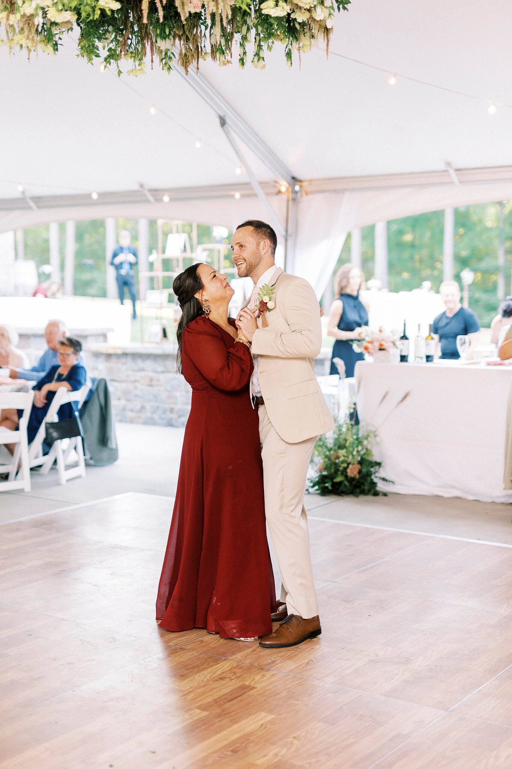 groom dances with mother under tent 