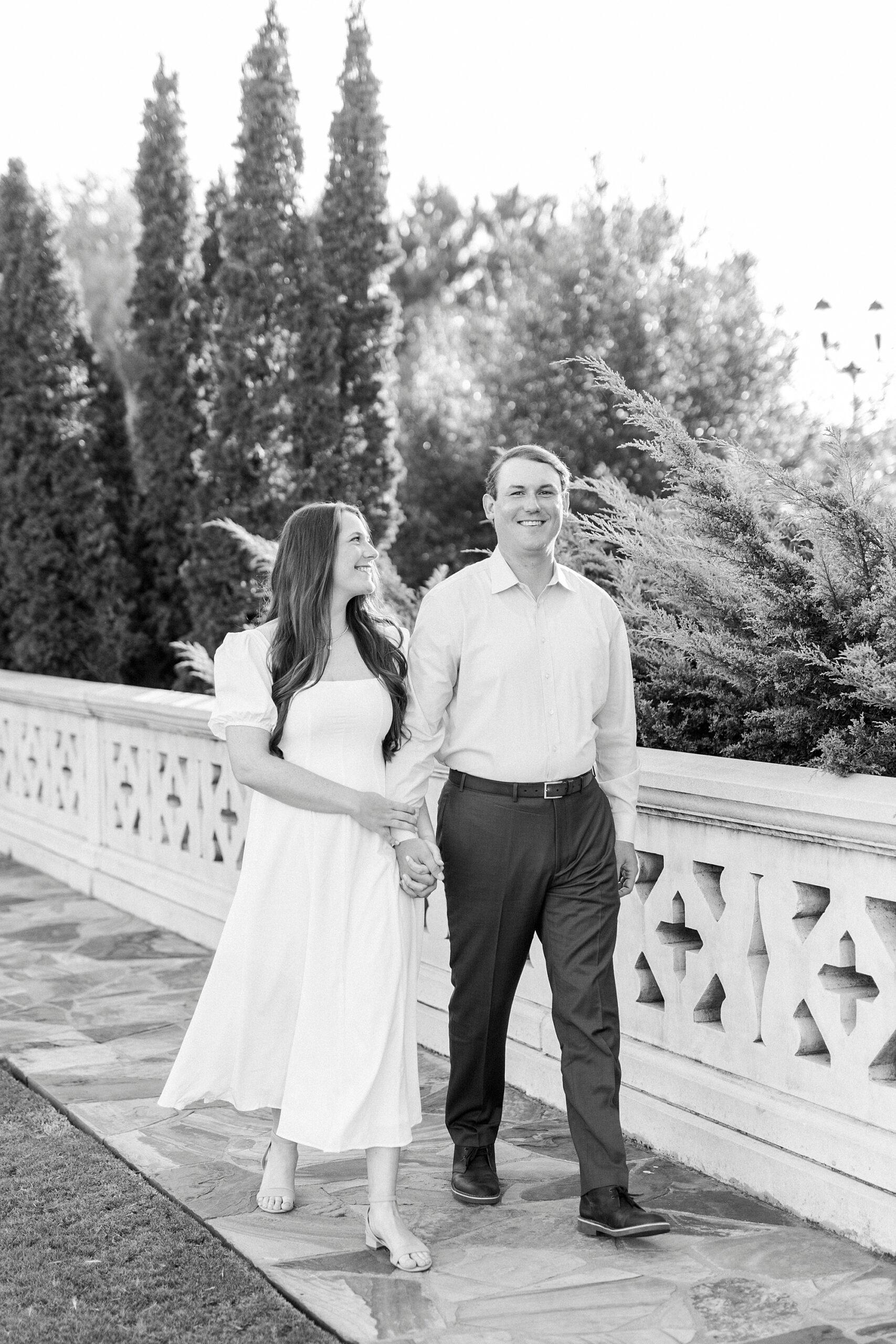 couple holds hands walking on bridge in Midtown Park