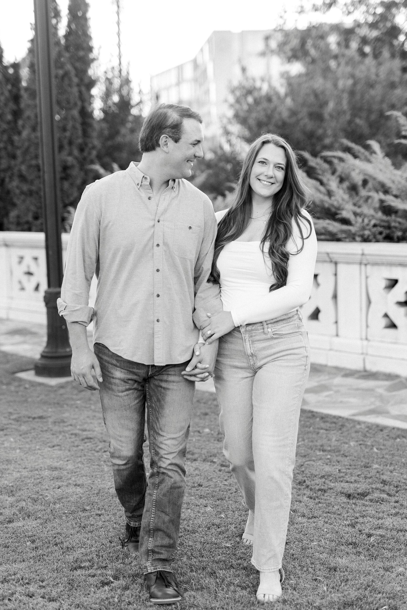 man and woman hold hands walking through park in Charlotte NC