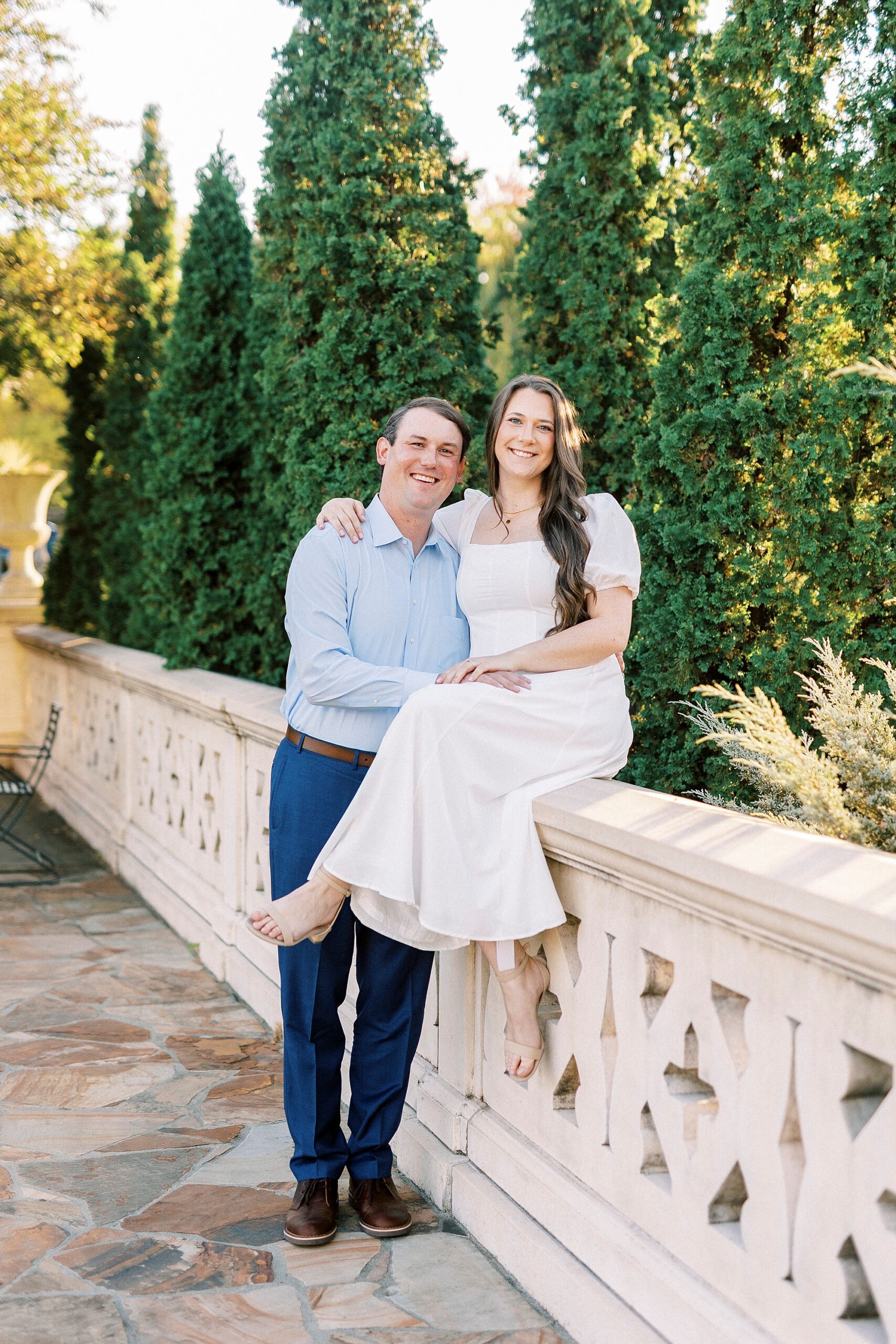 woman sits on side of bridge with fiancee next to her