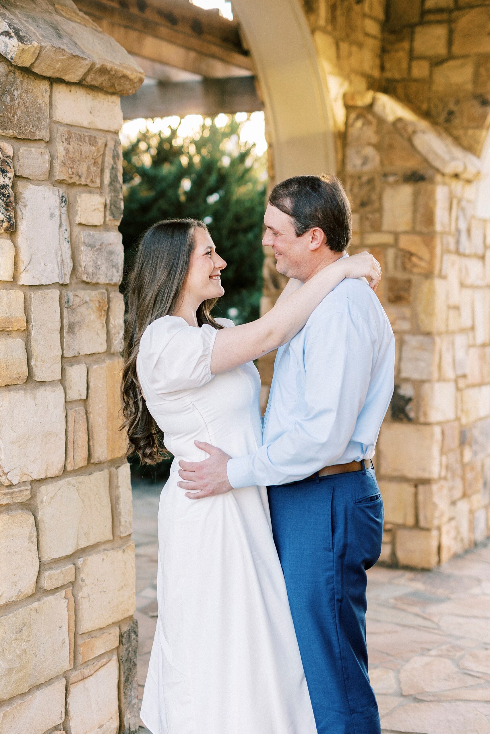 man and woman hug leaning into stone archways 