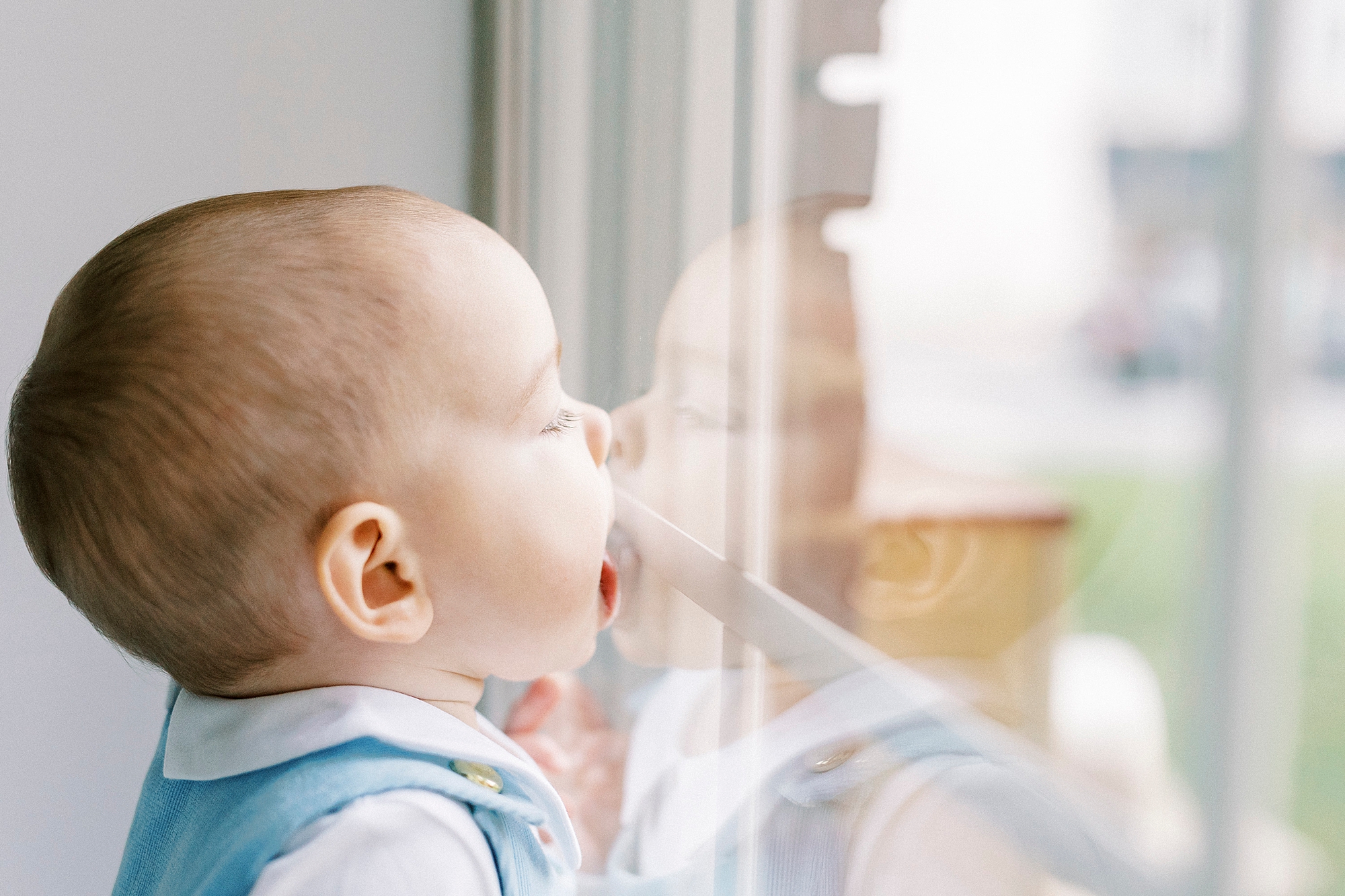 baby licks window during first birthday photos in Concord NC studio