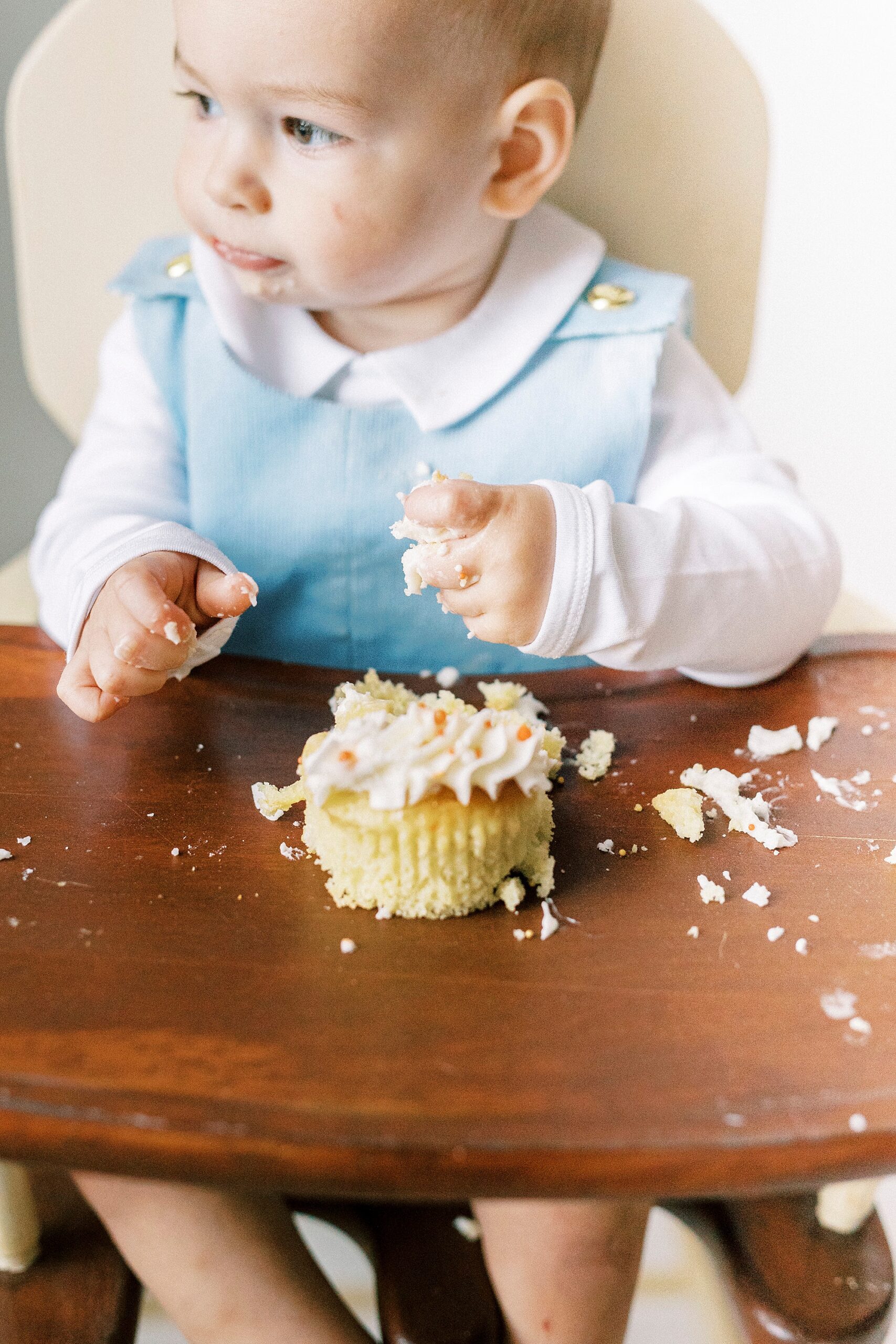 toddler plays with cupcake and icing during first birthday photos in Concord NC studio