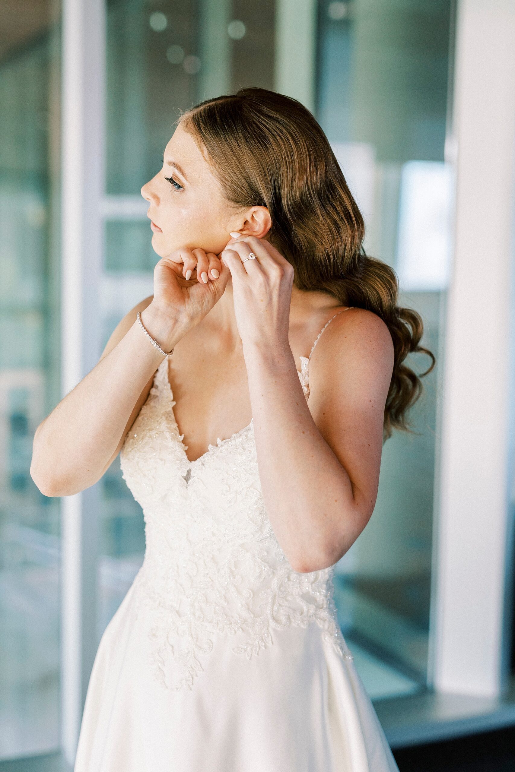 bride adjusts earrings inside suite at the Mint Museum Uptown