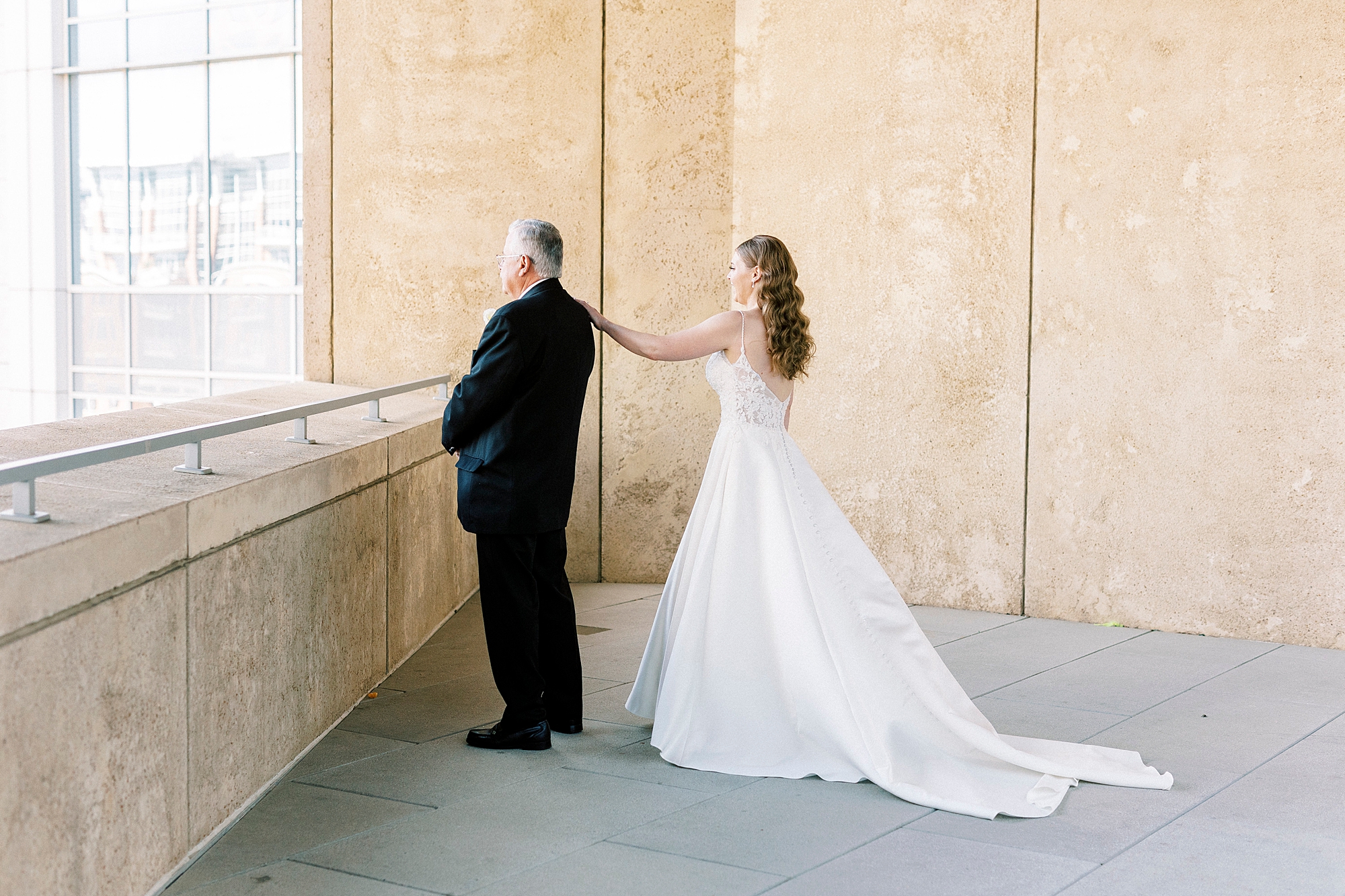bride reaches for dad's shoulder for first look on balcony at the Mint Museum Uptown