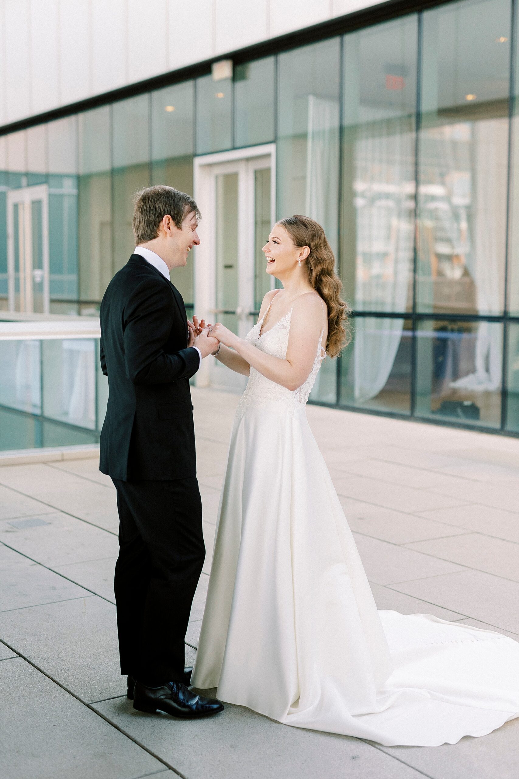 bride and groom grin during first look outside the Mint Museum Uptown