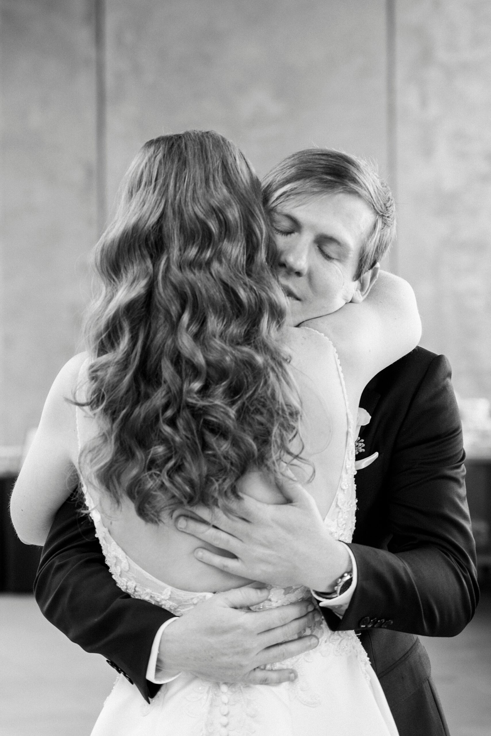 groom hugs bride during first look inside the parking deck at the Mint Museum Uptown