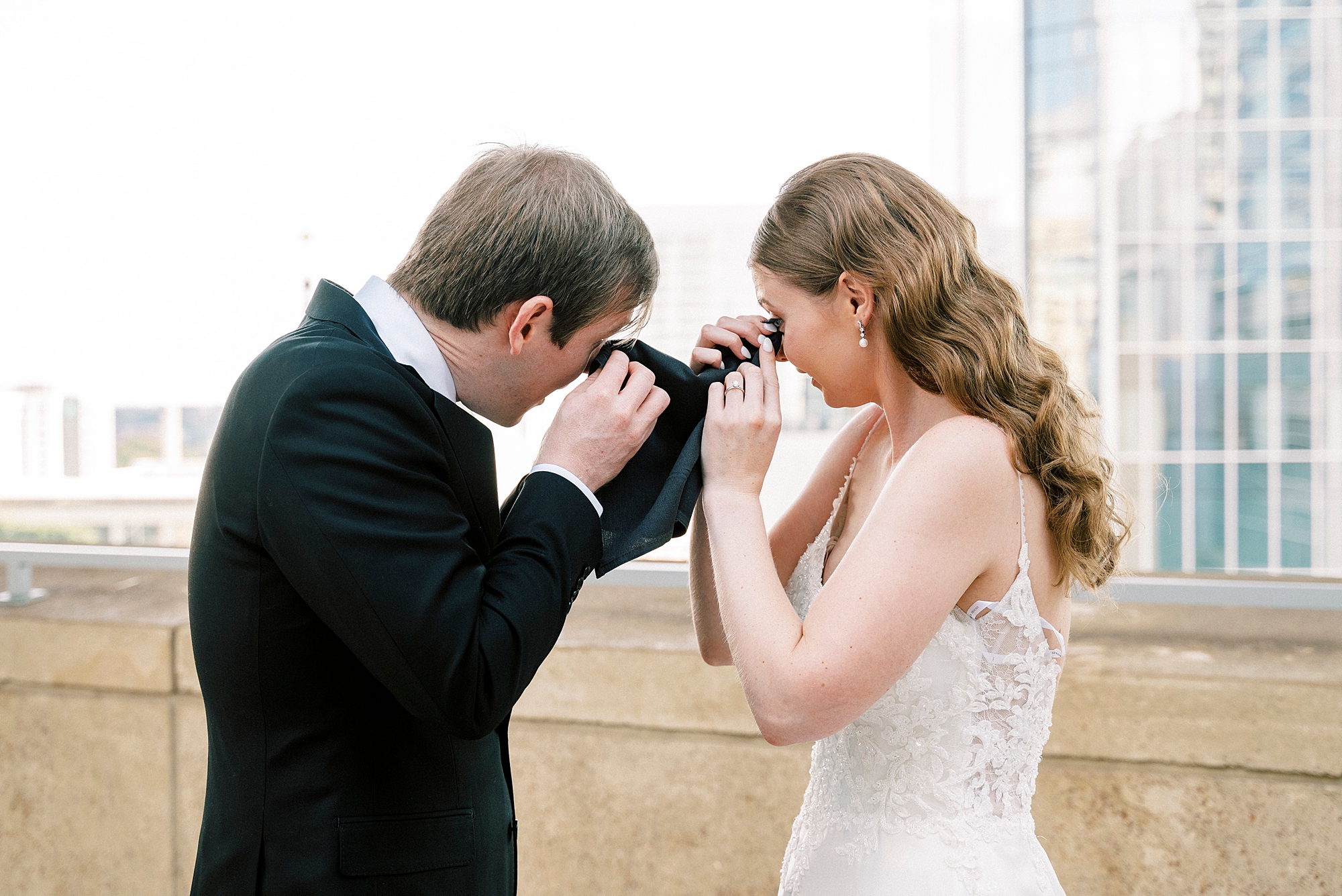 bride and groom cry holding handkerchief between them
