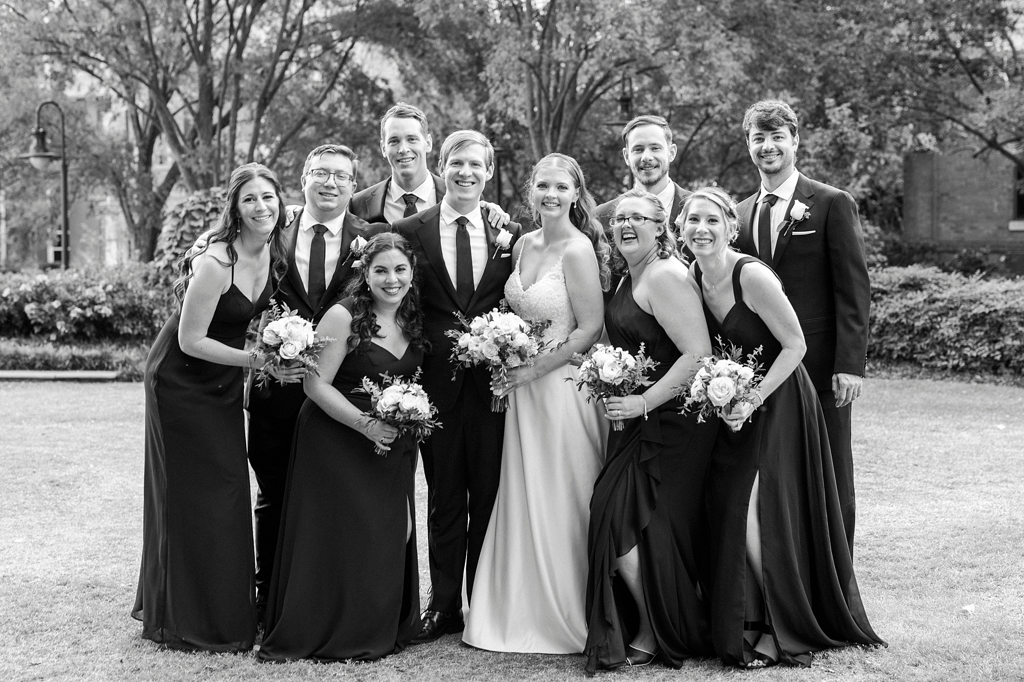 bride and groom hug with wedding party close around them in Charlotte NC park