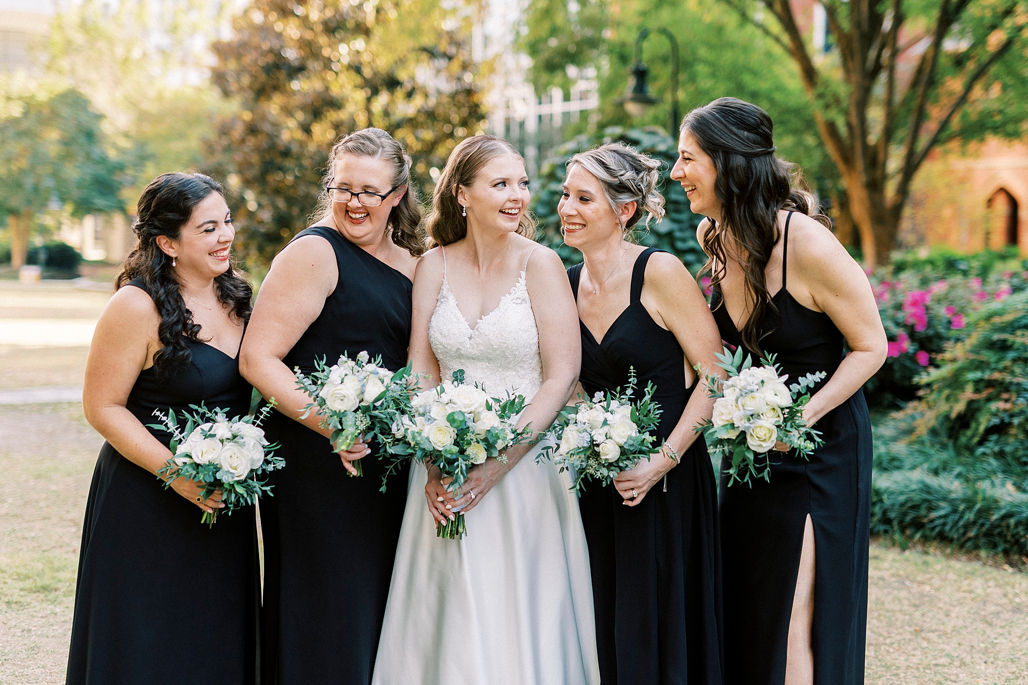 bride and bridesmaids smile laughing together with white flowers