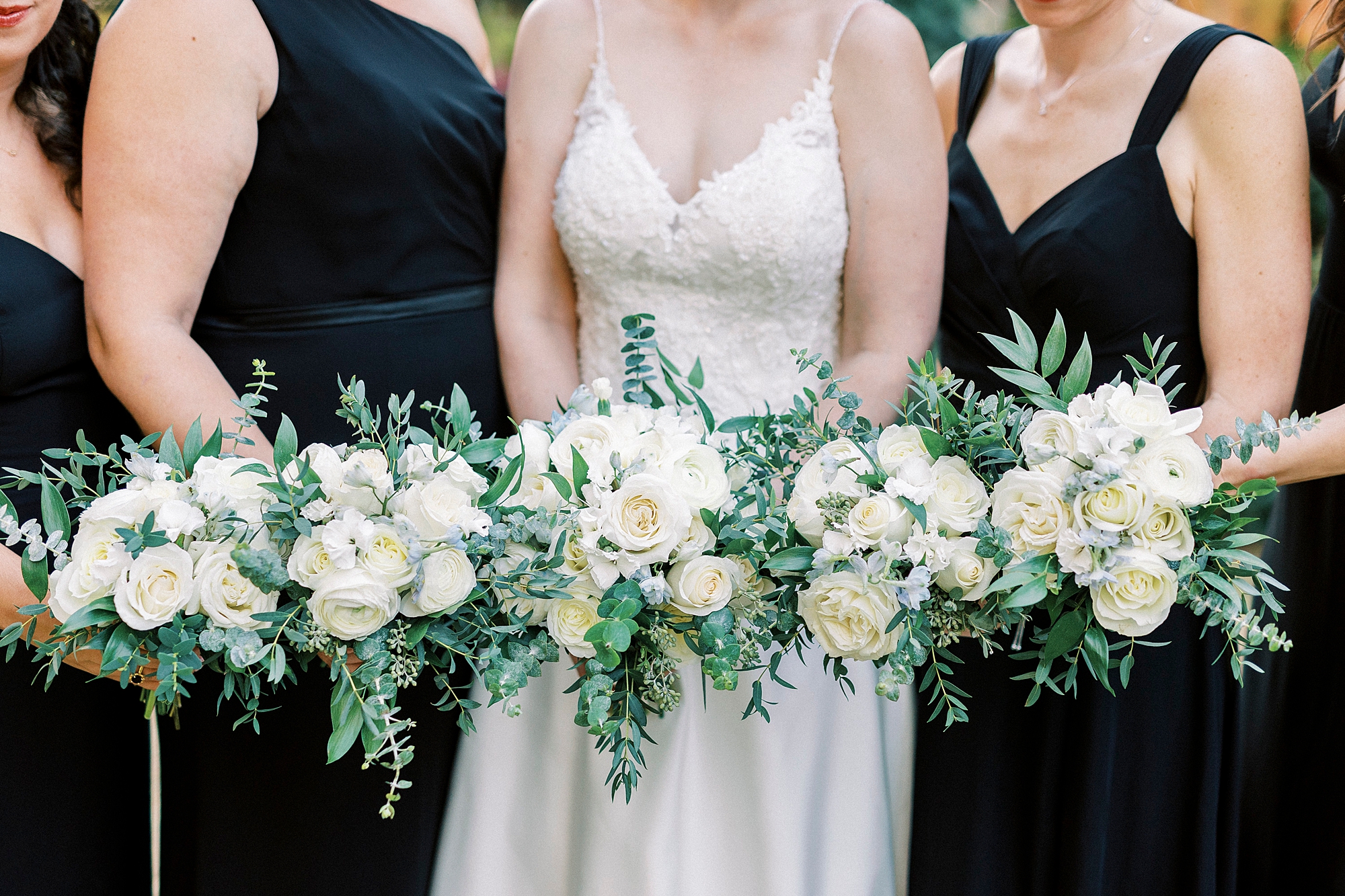 bride and bridesmaids hold white bouquets in black dresses