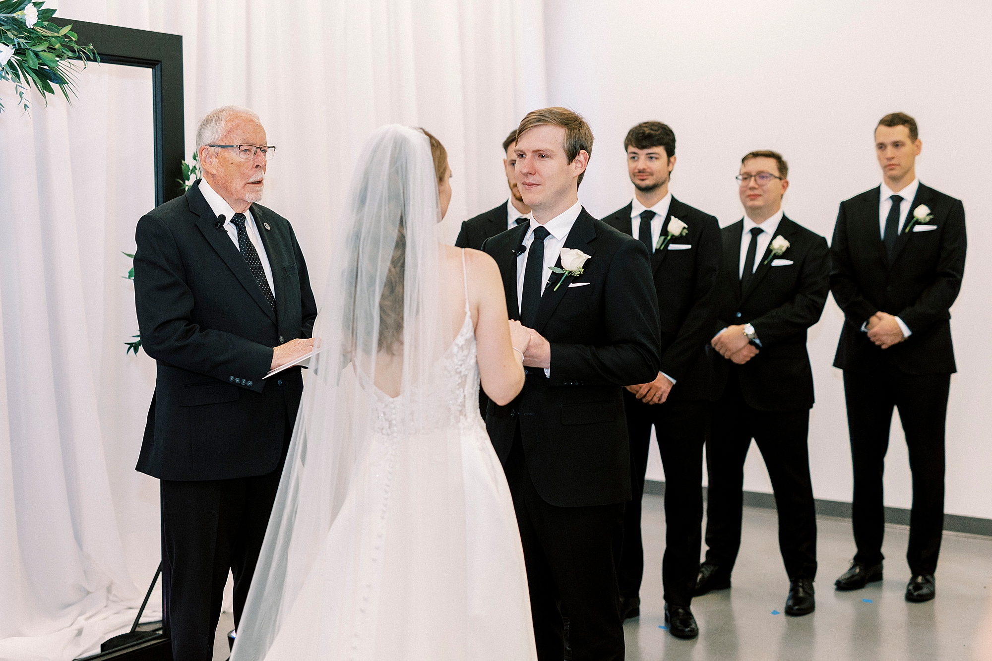 bride and groom hold hands during ceremony inside the Mint Museum Uptown