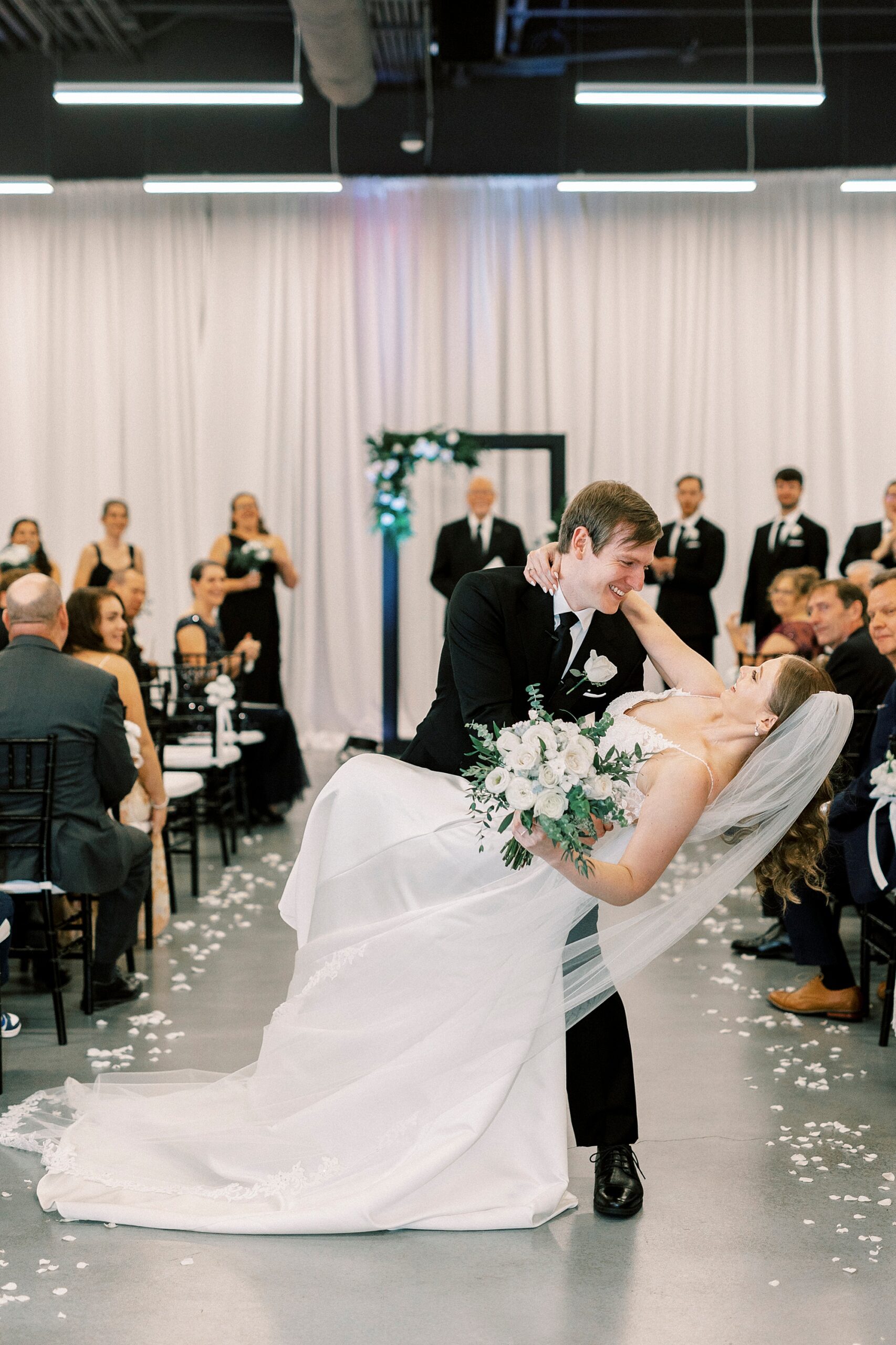 groom dips bride in aisle of ceremony at the Mint Museum Uptown