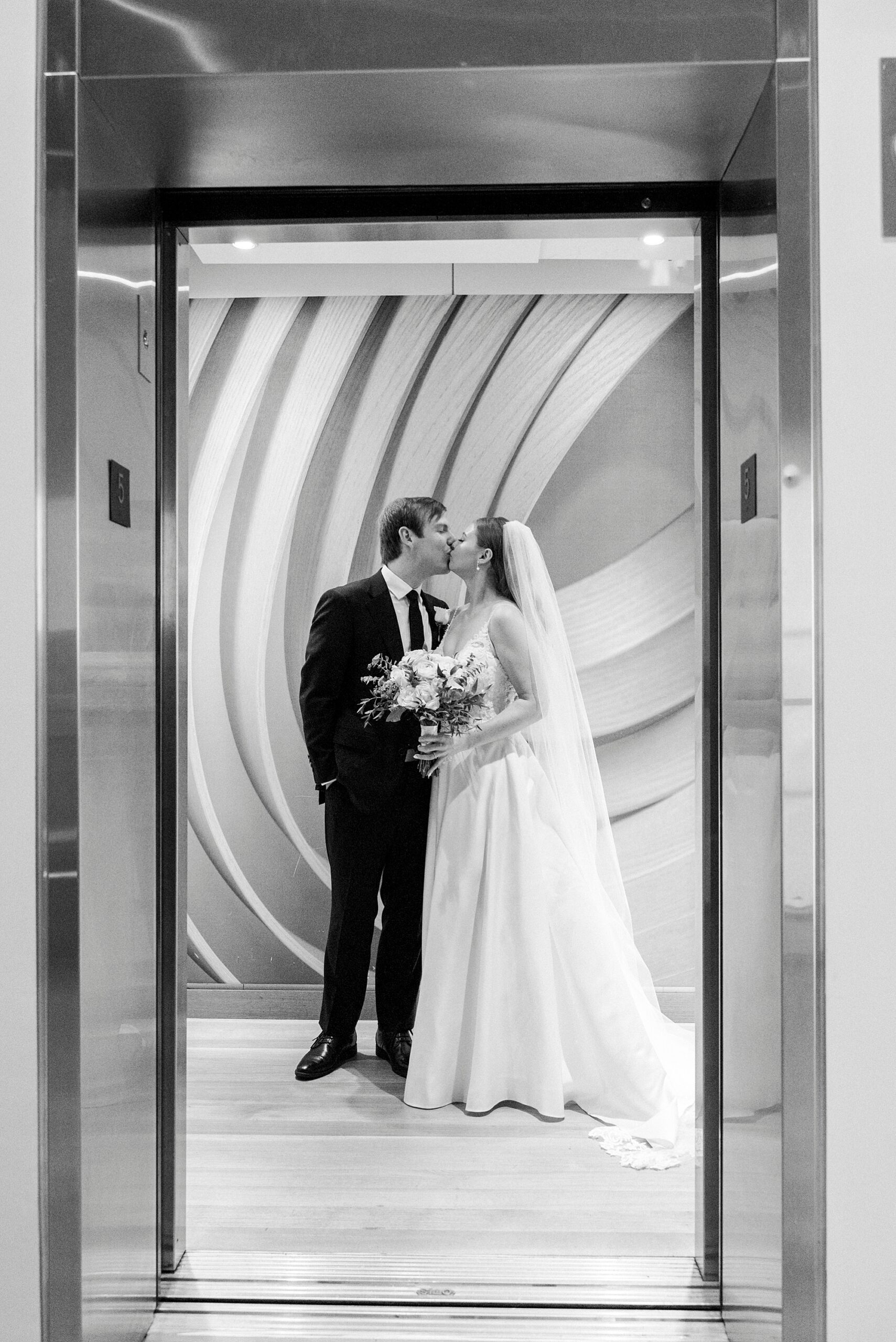 bride and groom kiss in the elevator at the Mint Museum Uptown
