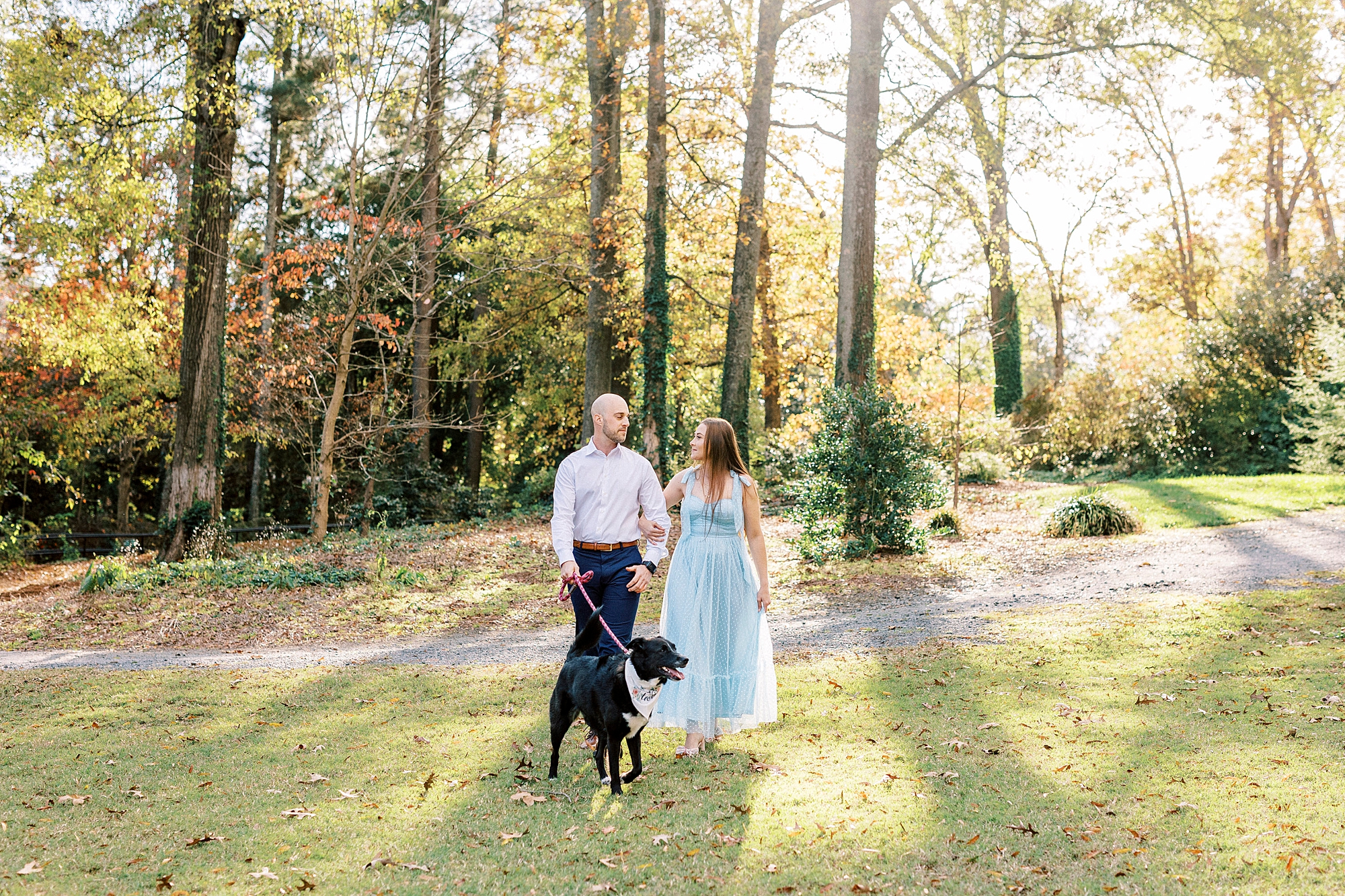 man and woman hold hands with black dog in front of them at Glencairn Garden