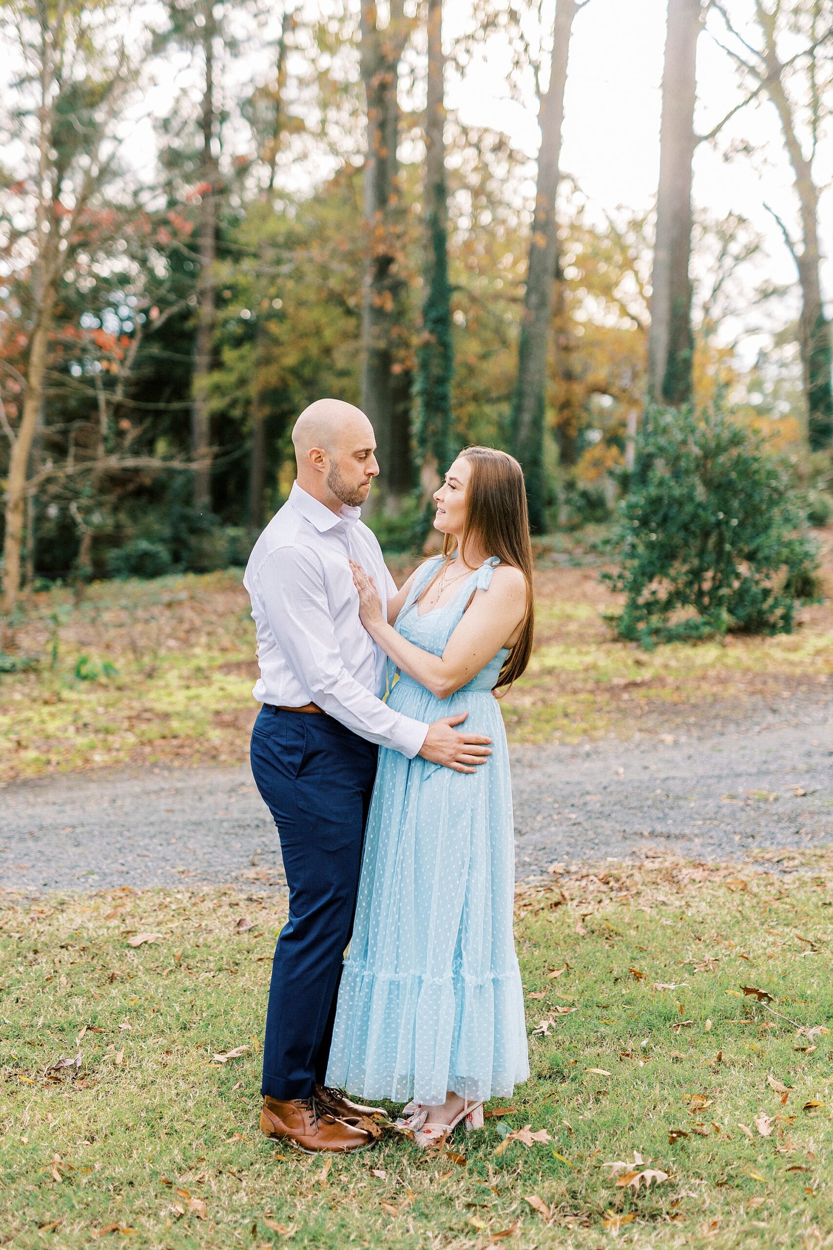 engaged couple hugs by walkway through Glencairn Garden
