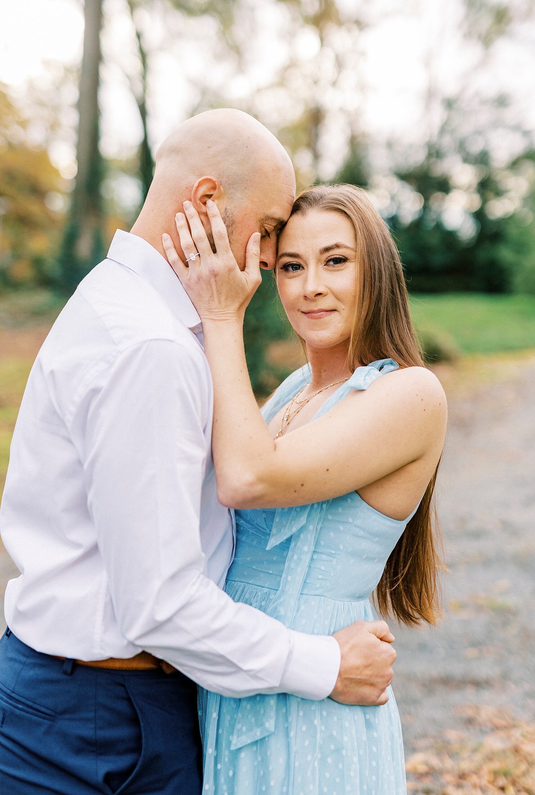 man nuzzles woman's forhead during engagement session at Glencairn Garden