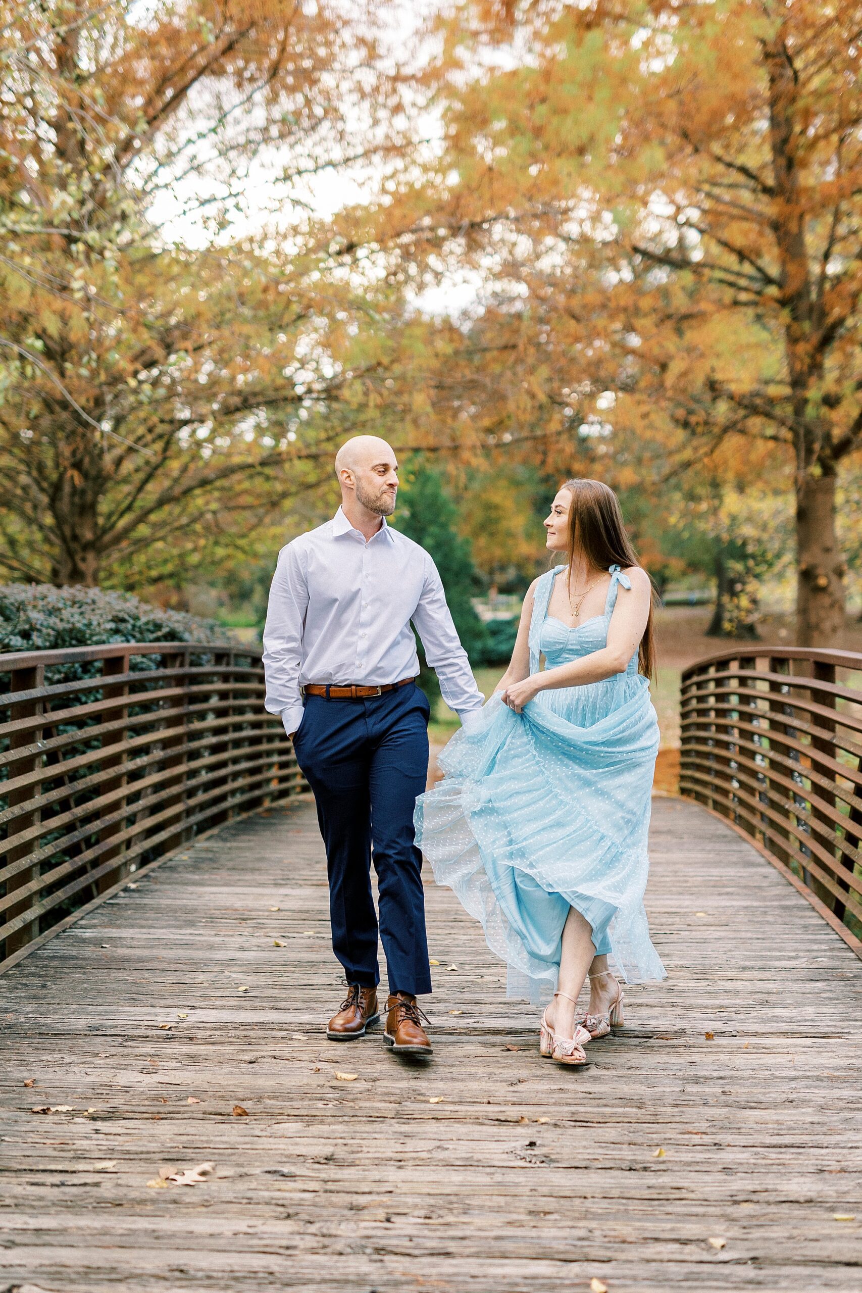 woman twists skirt while walking on wooden bridge inside Glencairn Garden